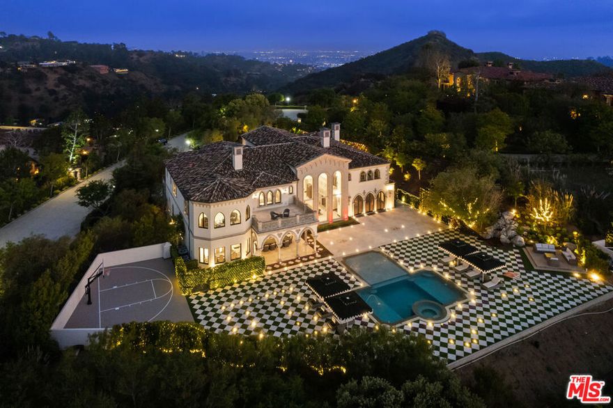 An enchanting property steeped in unrivaled elegance, 9 Beverly Ridge Terrace is utterly unparalleled in its design, scale and style. Custom-crafted by renowned designer Robert Rivani, the home fuses ultra-romantic details and modern conveniences with a divine Italianate aesthetic. Comprising seven all-ensuite bedrooms and nine baths, this three-level home spans 15,200 square feet on 1.7 acres of park-like grounds poised to host epic, large-scale gatherings and picture-perfect intimate soirees. Set behind the double-guarded gates of Beverly Ridge Estates, 9 Beverly Ridge immediately makes an indelible impression. Wind through a large motor court with a central fountain to arrive at the curved stone entry, which opens to reveal a foyer with triple-vaulted ceilings, walls of windows that frame incredible canyon views, crown-like chandeliers and medieval-inspired wall sconces. From here, a curved wrought-iron-railed staircase leads to the upper levels, while polished stone and hardwood floors beckon to grand main-level living spaces. Rooted in imaginative design, this home's distinct features and one-of-a-kind spaces delight at every turn. On the main level, a fantastical lounge with walls and ceiling covered with life-like faux flowers and a 300-piece chandelier resembling butterflies, creating a wonderland-like garden room. The gourmet kitchen boasts stone counters, an eat-in island and stainless steel Viking appliances. A bar room is replete with intricately carved coffered ceilings and a formal dining room is illuminated by the estate's signature crown-like chandeliers. Ascend to the second level's 2,000-square-foot primary retreat to find a bespoke wood fireplace, private terrace and spa-like bath with soaking tub and oversized steam shower.  Set on a rare flat lot, one of the community's largest, the estate's exquisite backyard features jet-liner canyon and sunset views and a pool and spa surrounded by a lounge area with harlequin-patterned pavers laced with squares of grass and flowers. Thoughtful outdoor amenities also include a sports court and a covered patio. Additional estate features include a library, gym, a six-car subterranean garage and smart home technology.  9 Beverly Ridge Terrace is located mere minutes from the shops, and restaurants of downtown Beverly Hills, and sits within the coveted Beverly Hills Post Office district.