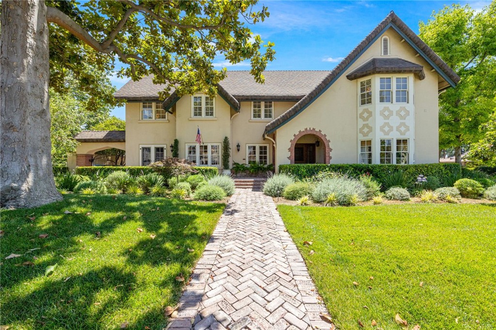 Step inside this magnificent 100 YEAR OLD gated Tudor Revival home located inside of Riverside's historic Wood Streets and experience a timeless blend of classic architecture and modern amenities. The BEAUTIFULLY LANDSCAPED exterior boasts quintessential elements of the style, including a steeply pitched roof, a stucco façade with brick accents.
Inside, the grandeur continues. The living room is anchored by a stunning Gothic stone fireplace, flanked by built-in bookshelves that add both function and elegance. Adjacent to the living room is a spacious office with its own AC unit, ensuring comfort and privacy. The oversized dining room exudes warmth and sophistication, while the custom iron railings on the staircase add a touch of artistry to the home’s design.
This residence offers four bedrooms and two full bathrooms, plus a small office nook upstairs for added convenience. The downstairs features a cozy bedroom, located off the dining room. UPSTAIRS IS GRACED WITH FOUR LARGE BEDROOMS. The primary bedroom is particularly impressive, with expansive views of the landscaped lot and the mature trees that surround it. The en-suite bathroom is a luxurious retreat, complete with a spa jacuzzi tub, walk-in shower, and dual sinks. The walk-in closet in the primary bedroom is spacious and thoughtfully designed.
The updated kitchen is a chef’s dream, offering plenty of space with granite countertops, double sinks, and a built-in refrigerator. The large island features a wine refrigerator, and there's an abundance of storage cabinets. A PROFESSIONAL Viking 6-burner gas range WITH TWO OVENS will inspire any home cook, while the adjoining breakfast nook adds a cozy spot to start the day. The laundry room is located just off the kitchen.
The home is set on a large walled lot, beautifully landscaped in the style of an English garden. The brick pavers in the garden comes from a historic brickyard in Chicago, adding a rich, vintage touch. A luxurious European-inspired pool and spa are the focal points of the backyard, with a delightful patio area that overlooks the water. A second patio close to the kitchen on the side of the house with BBQ hookups is perfect for entertaining.
Modern upgrades include efficient split AC units in the bedrooms and the large downstairs office, ensuring optimal cooling throughout the home. OWNED SOLAR! A three-car garage with 240V EV power is located at the rear of the property, and a basement for additional storage.