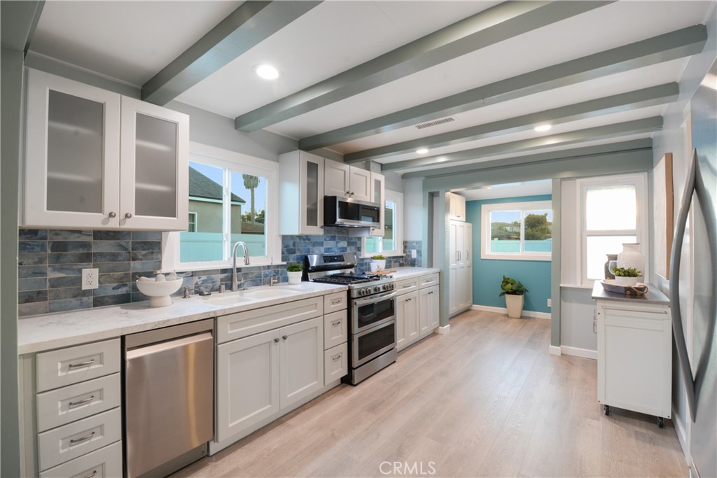 Welcome to a fully reimagined home in the highly desirable Vista Del Oro neighborhood of San Pedro. This turnkey residence offers 1-bedroom, 1-bathroom, and a completely finished 2-car garage that lives like additional interior space. Step into the welcoming living room, where an open layout flows seamlessly into the kitchen. The newly upgraded kitchen is a showstopper with coastal-inspired finishes, sleek matte quartzite countertops, a Kohler signature sink in Sea Salt with a push button disposal, crisp white cabinetry, modern blue/grey backsplash, ample cabinetry for storage, and sparkling stainless steel appliances, including a double-oven stove, refrigerator, microwave, and dishwasher. A versatile rolling island provides extra prep space, while the eye-catching beamed ceiling adds a warm architectural detail. For added convenience, the kitchen includes a reverse osmosis water filtration system and bright recessed lighting. The newly remodeled bathroom features a Kohler pedestal sink, tile flooring and fresh paint, and a classic clawfoot bathtub that elevates the space with timeless elegance. The home is filled with stylish details, including brand-new laminate plank flooring for easy maintenance, recessed lighting, ceiling fans in both the living room and bedroom for added comfort, and a unique planked ceiling that adds rustic, cottage-style charm. The home is equipped with a forced-air HVAC system with an integrated air scrubber and heat pump, dual paned windows, and newly insulated attic, ensuring year-round comfort. A new tankless water heater provides energy efficiency, while upgraded electrical wiring adds peace of mind. Step out the back door to discover an expansive backyard with a TimberTech deck and covered patio area, perfect for entertaining or relaxing outdoors. Other highlights include drought-friendly landscaping, a shaded patio awning, durable vinyl fencing, electric driveway gate, and earthquake retrofitting, offering added protection and confidence. The detached, completely finished two-car garage is a major bonus living space, featuring new drywall, high ceilings, recessed lighting, durable epoxy flooring, and a unique cubby space. Exterior washer/dryer hookups and a new garage door, this space is versatile enough to be used as an office, or considered for an ADU conversion. Ideally located, you’ll be close to shops, dining, parks, and San Pedro’s new waterfront. 2311 S Meyler Street is not just a home. It’s a lifestyle.