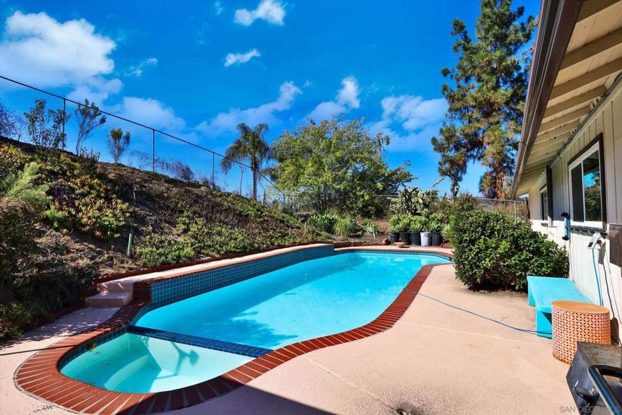 Resort-like hillside home with heated pool and spa. Amazing views on a quiet, private, no outlet street with great neighbors. Away from the noise, but just minutes from convenient shopping and access to recreation at local lakes and hiking trails. Underground utilities make for an amazing 180 degree view overlooking Winter Gardens and Eucalyptus Hills to Iron Mountain and Mount Woodson. Large parking pad for 3 cars plus boat/rv parking at street level with water spigot. Upgraded kitchen with custom cabinets, granite counters and all stainless steel appliances. Bathrooms include a new low flush toilet, all new brushed nickel faucets and matching cabinet handles, as well as new shower diverters. Entry, hall and large dining room feature hand hewned wood plank looking ceramic tile for a luxurious look with durability. Huge living room with wood/gas fireplace has solid exposed beam and incredible sunset views, with access to the large balcony offering even more views and a peaceful escape for morning coffee, watching local hawks and other wildlife or star gazing at night. Outside, the pool and spa have all new equipment, including programmable variable speed pump, gas heater and filter unit, as well as a Dolphin robotic pool cleaner, remote controlled multi-colored pool light and new pool tools. The backyard is fully fenced with separate dog run on side. There is a multipurpose storage/workshop/pool house with extended patio cover to finish as you see fit. New smart 8-zone sprinkler controller and valves. Fully owned solar w/ smart inverter results in near zero electric bills.  Central heat and air conditioning with a new smart thermostat, plus a whole house fan and an automatic attic fan keep the house comfortable throughout the year, plus the large living room ceiling fan with remote and ceiling fans with lights in every bedroom provide added comfort. All windows are dual-paned and energy efficient, providing added cost savings, comfort and quiet. Full-sized newer front loading washer with steam and electric dryer also convey, along with a new (stil in unopened box) hybrid (heat pump/element) water heater, that requires a new dedicated electrical connection. Other new items include a smart video doorbell, carbon monoxide detector, designer switches with dining room dimmer, motion activated hall, stairway and kitchen under-cabinet lights. Motion activated security lights at the garage, stairs and front door. Solar lights in the front planter and along the driveway. Low maintenance, mostly succulent, landscaping with low water demand.  This amazing property is move-in ready with opportunities to make finishing touches at your leisure. Priced below market, sellers are motivated to sacrifice it as they downsize.