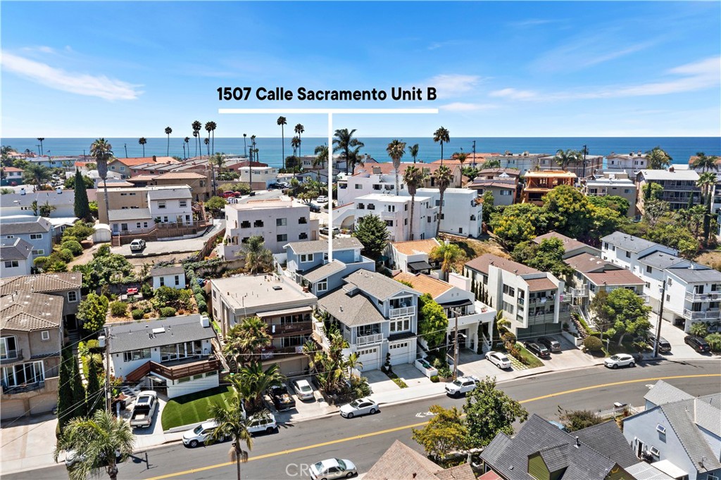 Located in the heart of North Beach, this contemporary coastal condominium designed by renowned local architect Jack Garland and built in 2019 pairs sophisticated seaside style with an unbeatable location. Situated as the rear unit of an intimate two-residence building, this 3-bedroom, 2.5-bath home lives like a single-family residence, sharing only one common wall and offering the freedom of no HOA dues. Spanning two stories, it showcases a bright, open floor plan with vaulted ceilings, a gourmet kitchen with a granite island, walk-in pantry, and high-end appliances. The upstairs primary suite is a refined retreat with beamed ceilings, a generous walk-in closet, a spa-inspired bath featuring a freestanding tub and separate shower, and exclusive access to the 318 sq ft rooftop deck where panoramic easterly views of hills and city lights create one of San Clemente’s most unique perspectives. Two additional bedrooms are located on the main level. A standout feature is the expansive 642 sq ft garage, rare for the area, equipped with EV charging, abundant storage, and space for multiple vehicles. Paid-off solar provides energy efficiency and cost savings, while a dedicated laundry room adds everyday convenience. All this is just a short walk to North Beach, the San Clemente Beach Trail, the iconic Ole Hanson Beach Club, The Casino, and an array of dining options including the highly anticipated Miramar Food Hall.