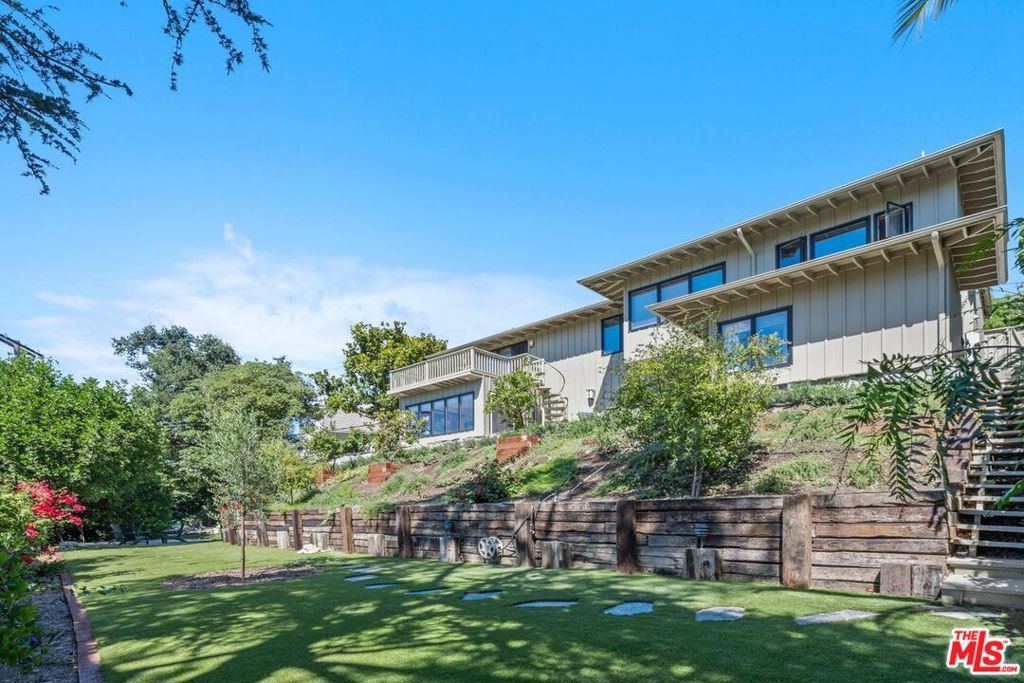 Discover a stunning Mid Century-inspired two-level home with panoramic views of the San Fernando Valley. From the living room, look through a wall of windows that opens to an unobstructed view of hundreds of trees and the San Fernando Valley that stretches all the way to the mountains beyond. The view opens in front of you from every room in the well-appointed home. The first floor's open plan includes high ceilings, a large gourmet kitchen with breakfast area, newly refurbished Viking 6 burner stove and range hood, extra deep marble countertops and beautiful cabinetry, pantry, storage closets and laundry area. The living room is a comfortable gathering place with beautiful custom shelving and cabinetry and a dining area for entertaining that has access to an open deck, a perfect location for a sunset supper or morning coffee. Downstairs, the primary bedroom has windows and glass sliders, a walk-in closet, an additional closet and a large primary bath. Sliding doors in the bedroom give easy access to a shaded garden area, the large patio and stone steps that lead down the landscaped hillside to the grass area below. It's a perfect place for kids and pets to romp and play. The family room connects the primary bedroom area to two additional bedrooms and an art deco style bathroom. One bedroom is currently used as an office and has a large separate storage area. Sliding doors from the family room and bedroom open to the large patio. Extras include easy access to hiking trails, nearby restaurants, Dixie Canyon Charter and other schools, owned solar panels which provide 40-70% of the power to run the home, whole house water filter and an e-plug in the garage. This is truly a special home, well cared for and with a million-dollar view.
