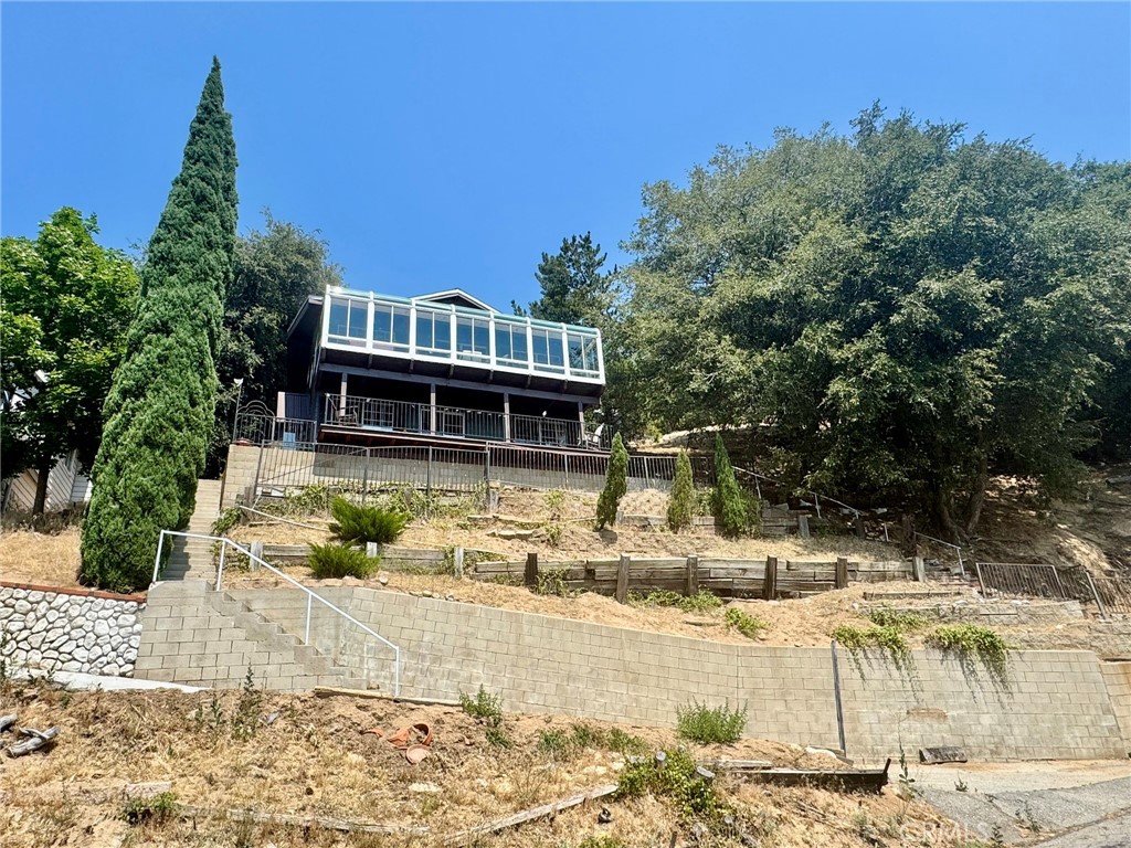 This charming 3 bedroom, 2 bathroom is perched on a hillside in the San Moritz area of Crestline provides panoramic views of Lake Gregory. There is a full bath on each level, 2 bedrooms on the main floor. The downstairs level features a third bedroom and a room with access to the deck that can easily function as a fourth bedroom. The kitchen has stainless steel appliances and wood cabinets that match the pitched tongue and groove ceiling that extends into the living room. There is a freestanding stove in the corner adding to the charm of this special property. The loft area is separated from the living area by just a few steps and wrought iron railing. This area could easily be used as a dining room, office space, play area, or reading nook. The laundry area of this home is located on the landing between the first and second floors for easy access. The thing that truly sets this property apart is the large completely covered deck which functions as a sunroom. The large windows in this area provide expansive, breathtaking views that are the first thing that can be seen as soon as you enter the property. Newer copper plumbing and newer roof. The home has been well cared for and features brand new exterior paint and new carpeting ensuring the new homeowners can move right in and call this property home.