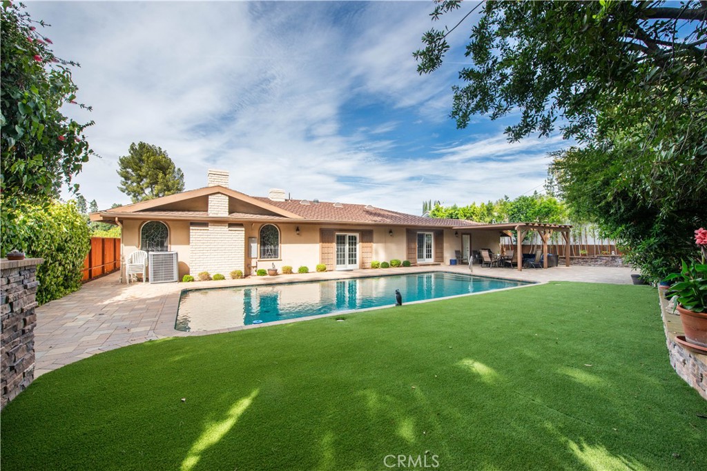 Welcome to this elegant single-level residence, ideally situated South of the Boulevard in one of Encino’s most sought-after locations. Set above the street for added privacy and curb appeal, this home offers an exceptional layout designed for both comfort and entertaining. Step through the formal entry into a grand living room anchored by its central fireplace, flowing seamlessly into the expansive formal dining area—perfect for gatherings and celebrations. Enjoy a culinary experience in the updated contemporary kitchen, complete with custom cabinetry, stainless steel appliances, granite countertops, and a sunlit breakfast area. The warm and inviting family room is enhanced by rich wood-beamed ceilings, cozy fireplace, classic built-in bar, and a versatile office retreat—ideal for working from home or unwinding with family. Outfitted with three generously sized bedrooms, including a sprawling primary suite with a sitting area, dual closets (walk-in and wardrobe), dressing area, and a luxurious spa-inspired bath showcasing a freestanding soaking tub, seamless glass two-person shower, and private commode room. Step outside to enjoy an ultra-private backyard oasis, featuring expansive open and covered patio areas, updated pavers, stacked stone accents, and a true swimmer’s pool surrounded by lush mature landscaping—creating the perfect space for relaxation and entertaining. Located just moments from Lanai Road Elementary School, along with convenient Westside access. Dont miss your opportunity to call this exceptional Encino residence home!