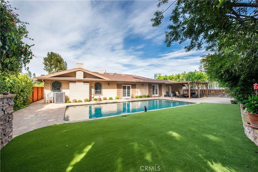 Welcome to this elegant single-level residence, ideally situated South of the Boulevard in one of Encino’s most sought-after locations. Set above the street for added privacy and curb appeal, this home offers an exceptional layout designed for both comfort and entertaining. Step through the formal entry into a grand living room anchored by its central fireplace, flowing seamlessly into the expansive formal dining area—perfect for gatherings and celebrations. Enjoy a culinary experience in the updated contemporary kitchen, complete with custom cabinetry, stainless steel appliances, granite countertops, and a sunlit breakfast area. The warm and inviting family room is enhanced by rich wood-beamed ceilings, cozy fireplace, classic built-in bar, and a versatile office retreat—ideal for working from home or unwinding with family. Outfitted with three generously sized bedrooms, including a sprawling primary suite with a sitting area, dual closets (walk-in and wardrobe), dressing area, and a luxurious spa-inspired bath showcasing a freestanding soaking tub, seamless glass two-person shower, and private commode room. Step outside to enjoy an ultra-private backyard oasis, featuring expansive open and covered patio areas, updated pavers, stacked stone accents, and a true swimmer’s pool surrounded by lush mature landscaping—creating the perfect space for relaxation and entertaining. Located just moments from Lanai Road Elementary School, along with convenient Westside access.  Dont miss your opportunity to call this exceptional Encino residence home!