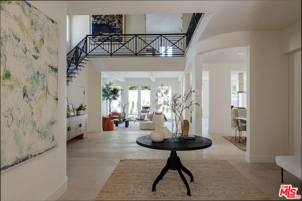 In one of Hancock Park's most coveted enclaves, this five-bedroom, six-bathroom home has been meticulously rebuilt with a refined, organic modern aesthetic. Earth-toned limestone and wide-plank hardwood floors set a quiet, grounded tone, while bespoke finishes and natural light bring depth and softness to every space. Three dramatic fireplaces, each wrapped in statement stone, anchor the main living areas with sculptural flair. In the den and kitchen, French doors invite the outside in, offering a seamless connection to the surrounding gardens, outdoor kitchen, and private pool. The kitchen flows effortlessly into both formal and informal spaces, perfect for entertaining and everyday ease. Upstairs, the spacious primary suite opens to a Juliet balcony and features a sitting area, a generous closet, and a spa-like bath. Each additional bedroom offers its own character, all en suite and filled with light. Outside, a sparkling pool and hot tub are framed by greenery, creating your secluded oasis in the city. Thoughtfully designed and layered with texture, this is a home that feels as good as it looks.