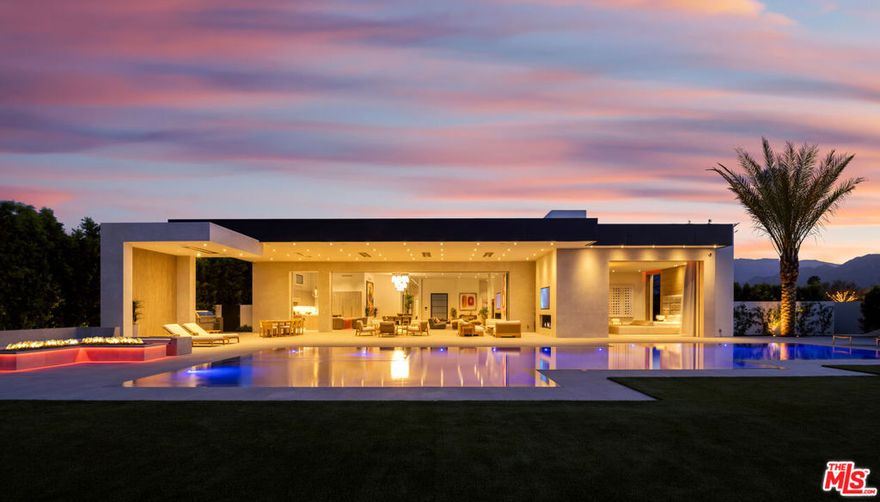 A breathtaking ultra-private warm contemporary estate showcasing explosive golf course and mountain views on one of the most coveted streets within the prestigious Madison Club. This residence combines top-tier design and construction with world-class interiors that create instant magic - an atmosphere that captivates from the moment you walk in and evokes the lifestyle dreams reserved for its fortunate future owner. Spanning more than 13,000 SF under roof (approx. 9,400 SF under A/C), the home features a flawless open floor plan with 9 beds, including 6 full bedroom suites and a remarkable 1,800 SF two-bedroom guest penthouse complete with fireplaces and sweeping mountain vistas. Entertaining is elevated with a state-of-the-art cinema, Italian main and chef's kitchens, bar lounge, and seamless indoor-outdoor living spaces. Amenities include a three-car garage with an additional golf cart garage, both tiled and enhanced with RGB lighting, plus a shaded carport and secure motor court. Outdoors, a zero-edge oversized pool is complemented by a fire pit lounge, covered loggia with four distinct seating areas, an outdoor living room with fireplace, extensive BBQ station, and a private primary patio featuring a spa, outdoor shower, and fire pit. The primary suite also boasts one of the most impressive closet and bath combinations imaginable.  The estate is complete with 16 televisions plus a 210" theater screening room powered by Apple TV, and best-in-class automation. Energy efficiency is maximized through a solar array paired with a 26-SEER modulating HVAC system.