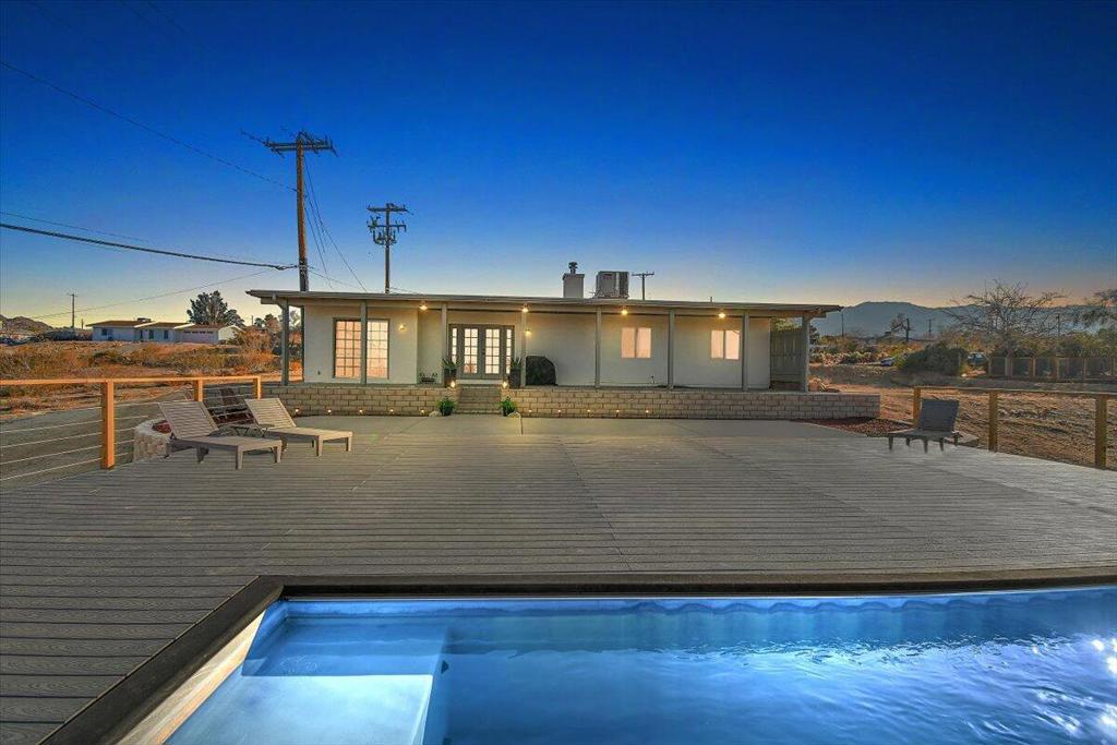 Beautiful remodeled 4-bedroom, 2-bathroom pool home with Solar on a large 15,000 sq ft lot located in the heart of Joshua Tree. This home is just a quick 5-minute drive to the Joshua Tree National Park entrance and only a few blocks from Joshua Tree Village. This fantastic property is perfect for entertaining with the large patio deck surrounding the pool and a firepit for those starry nights just below. This location makes it perfect as a primary residence, vacation home, or short-term rental!This property offers breathtaking desert views, ideal for stargazing from the spacious back patio, firepit area or while relaxing in the pool on sunny days. Enjoy magical desert nights under the covered patio, roast s'mores by the outdoor firepit illuminated by decorative string lights, and immerse yourself in the peaceful tranquility of the stunning views surrounding the open desert. Large driveway for RV Parking or your favorite sand toys.Inside, the home has been remodeled with a chic boho-modern aesthetic and can be sold furnished at the right price. Key features include a cozy wood-burning stove, stylish wooden shutters, stainless steel appliances, decorative light fixtures, a spacious walk-in closet, private laundry, an office space, and solar panels (buyer to assume the solar lease). *Seller owns adjacent vacant land to the left of the property and is willing to consider selling it as well. Don't miss this incredible opportunity! Schedule your private showing today