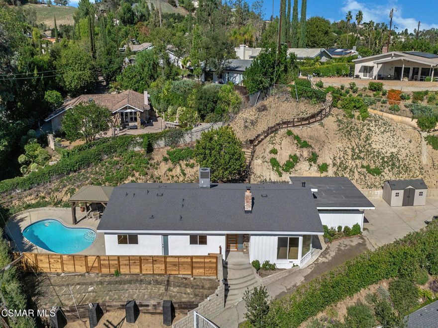 Private, gated mid-century single-story pool home with lots of natural light located in the prestigious Hana Valley of Woodland Hills. Drive up your private driveway which includes an electric gate for security and privacy. The home sits on almost a half-acre of land which includes a very serene wide patio area in the back of the home perfect for entertaining including a beautiful sparkling pool next to the master bedroom. Once you enter this very special home you will notice the extra-large glass windows in the living room emitting lots of natural light. Sit back and enjoy the views of the many surrounding mature trees while getting the warmth from the inviting fireplace. The kitchen has stainless steel appliances, ample white cabinetry, granite countertops, kitchen island with four burners and hood vent. Refrigerator, washer and dryer are included. Master suite has a sunken tub and view to outside pool area. The bedrooms in the front of the home have peaceful views of the beautiful mature trees. The house has beautiful wood flooring throughout. The living room wood floor was just refinished. Additionally, the roof is very new including new fascia boards, new windows throughout, new bathroom tiles, newer AC and ducts, new paint inside and outside, new piping under the house to the main line, new water filtration system. Additionally, the side yard may offer opportunities for an ADU. This beautiful home has so much to offer. Don't miss out on this great opportunity!