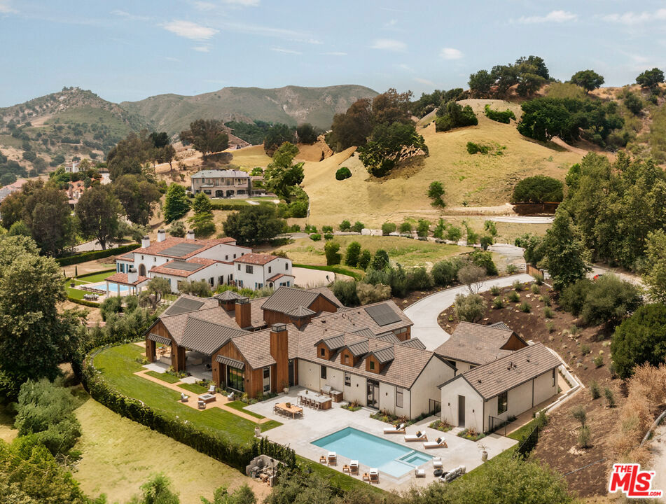 Tucked behind a long, private drive within the exclusive gates of Malibu Valley Estates, this brand-new construction Modern Ranch estate offers a sophisticated interpretation of California countryside living. Set amidst the rolling hills of the Santa Monica Mountains, the estate has been masterfully designed by one of Southern California's most exacting builders, with an emphasis on timeless materials, artisanal craftsmanship, and effortless indoor-outdoor flow. Sited on approx. 1.7 acres behind another set of gates, this 6000+sf single story home features 12-20ft soaring ceilings over and is comprised of a Main Residence, ADU, and Junior ADU - perfect for flexible and uniquely private living. Designed and curated to bring luxuriously rustic elegance to today's most discerning Buyer, finishes include Calacatta marble surfaces, engineered hardwood floors, solid core doors, imported lighting and fixtures, custom millwork, and walls of glass that frame the surrounding landscape in an abundance of light and serenity. Anchored by a dramatic great room and an elegantly appointed chef's kitchen, the interiors are designed for both grand-scale entertaining and modern conveniences such as Gaggenau and Thermador professional-grade appliances, a walk-in pantry, and an eat-in island. The primary suite is a true retreat, featuring 15-foot ceilings, a fireplace, a private covered patio, and a spa-like bathroom with dual vanities and a soaking tub. In addition to the main residence, the property offers a junior ADU and a fully independent guest house, each with its own distinct entrance and private living spaces - ideal for extended family, guests, or a dedicated office or studio. A series of outdoor living areas include multiple covered patios, a central courtyard with a fountain, enormous, covered patios, an expansive poolside terrace with an outdoor kitchen and pool bathroom, a grassy lawn, and endless spaces for entertaining. Offering unique possibilities for the avid equestrian, the lower portion of the lot is primed to add a barn or corral for horses just minutes from riding trails and a hunter/jumper equestrian center. The grounds are equally impressive, featuring mature landscaping including 100+ year-old olive trees, lavender-lined walkways, a sparkling pool and spa, and a romantic fire pit lounge - the ultimate retreat. This private estate embodies a rare opportunity to own a brand-new home in one of Malibu Valley's most coveted enclaves, a quick drive away from Pacific Coast Highway, US-101, Erewhon, Old Town Calabasas, and so much more. A retreat of enduring elegance, designed for those who value privacy, beauty, and exceptional living just minutes from the best hiking, biking, horseback riding, and nature-driven lifestyle Los Angeles has to offer.