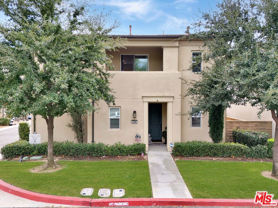 YOUR NEW HOME AWAITS IN BEAUTIFUL VILLA METRO! Welcome to resort-style living in the highly sought-after gated community of Villa Metro where modern design meets California charm. This stylish two-story detached home offers 2 bedrooms and 2 baths, featuring elegant wood-laminate flooring, plush carpeting, and designer accent walls throughout. The first-floor primary suite offers the perfect retreat with a private bath and sliding glass doors that open to your own tranquil patio.  Ideal for morning coffee or quiet evenings. The open-concept upper level is bright and airy, boasting a chef-inspired kitchen with crisp white cabinetry, stainless-steel refrigerator, and appliances. A center island with bar seating that flows seamlessly into the dining area and cozy living room. Step through the sliding door to your covered balcony, a perfect spot to unwind and enjoy the breeze. Down the hall, discover the charming custom sky-blue barn doors leading to your second bedroom with its own a full bath, stackable washer/dryer, and convenient hallway storage. Enjoy direct access to your two-car attached garage, plus all the perks of Villa Metro's resort-inspired amenities a sparkling pool and spa, kiddie pool, clubhouse, BBQs, fire pit, community garden, bike path access, playground, and scenic courtyards perfect for evening strolls. Ideally located just minutes from the Metrolink station, shopping, dining, Six Flags Magic Mountain, and top-rated schools. This corner home is filled with natural light and designed for comfort, convenience, and effortless living! Low Mello Roos $1,484.00