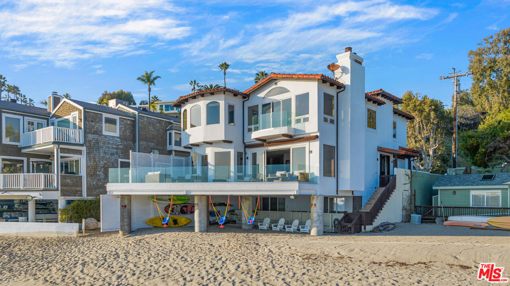 Discreetly positioned on the sand of Malibu's coveted Escondido Beach - one of the area's most private and sought-after shorelines - this gated, meticulously renovated home embodies refined coastal living. Set on a quiet residential street, the residence opens to a light-filled layout where soaring glass walls and an expansive oceanfront deck frame breathtaking panoramic views. The main level flows seamlessly from a sunlit living room into a designer kitchen with a grand center island and top-tier appliances. A spacious home office and powder room complete this level. Upstairs, the primary suite spans the width of the home, showcasing endless ocean vistas, a spa-inspired bathroom with steam shower, soaking tub, dual vanities, and a walk-in closet. Three additional en-suite bedrooms complete the top floor. The beach level floor plan offers a versatile great room that blends indoor and outdoor living, along with a fifth en-suite bedroom perfect as a guest retreat, gym, or office. Beneath the deck, a shaded sandy area with 50 feet of frontage creates a rare beachfront lounge with generous storage for surfboards, kayaks, and more. Additional features include a two-car garage, gated driveway with guest parking, central HVAC, and a wine fridge. Just moments from Geoffrey's and a short beach stroll to Paradise Cove, this oceanfront sanctuary places the best of Malibu's dining, shopping, and surf at your doorstep.