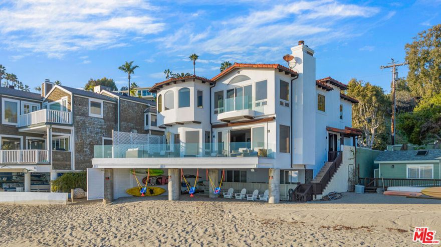 Discreetly positioned on the sand of Malibu's coveted Escondido Beach - one of the area's most private and sought-after shorelines - this gated, meticulously renovated home embodies refined coastal living. Set on a quiet residential street, the residence opens to a light-filled layout where soaring glass walls and an expansive oceanfront deck frame breathtaking panoramic views. The main level flows seamlessly from a sunlit living room into a designer kitchen with a grand center island and top-tier appliances. A spacious home office and powder room complete this level. Upstairs, the primary suite spans the width of the home, showcasing endless ocean vistas, a spa-inspired bathroom with steam shower, soaking tub, dual vanities, and a walk-in closet. Three additional en-suite bedrooms complete the top floor. The beach level floor plan offers a versatile great room that blends indoor and outdoor living, along with a fifth en-suite bedroom perfect as a guest retreat, gym, or office. Beneath the deck, a shaded sandy area with 50 feet of frontage creates a rare beachfront lounge with generous storage for surfboards, kayaks, and more. Additional features include a two-car garage, gated driveway with guest parking, central HVAC, and a wine fridge. Just moments from Geoffrey's and a short beach stroll to Paradise Cove, this oceanfront sanctuary places the best of Malibu's dining, shopping, and surf at your doorstep.