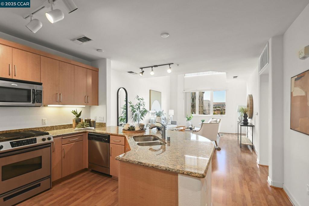 Discover urban living at its finest in this stunning 2-bedroom, 2-bathroom condo, perfectly located just minutes from Dublin BART, shopping, dining, and easy freeway access to 580/680. Boasting an impressive 1,399 sq. ft. two-level layout with soaring vaulted ceilings, this home blends space, style, and convenience. The open-concept living and dining area features beautiful laminate flooring, recessed and track lighting, and a private balcony with breathtaking mountain views. The gourmet kitchen is a chef’s dream with granite countertops, stainless steel appliances—including a double-door refrigerator and gas range—plus a double basin sink with pull-out faucet. The luxurious primary suite offers a large walk-in closet and spa-like bath, while the second bedroom and full bath provide flexibility for guests or a home office. Additional highlights include in-unit front-loading washer/dryer, central heat and A/C, and two secure parking spaces in a gated garage. Enjoy resort-style amenities—fitness center, game room, social lounge, and lush landscaped courtyard—all in a prime Dublin location where everything is within reach. Welcome home to luxury, location, and lifestyle!