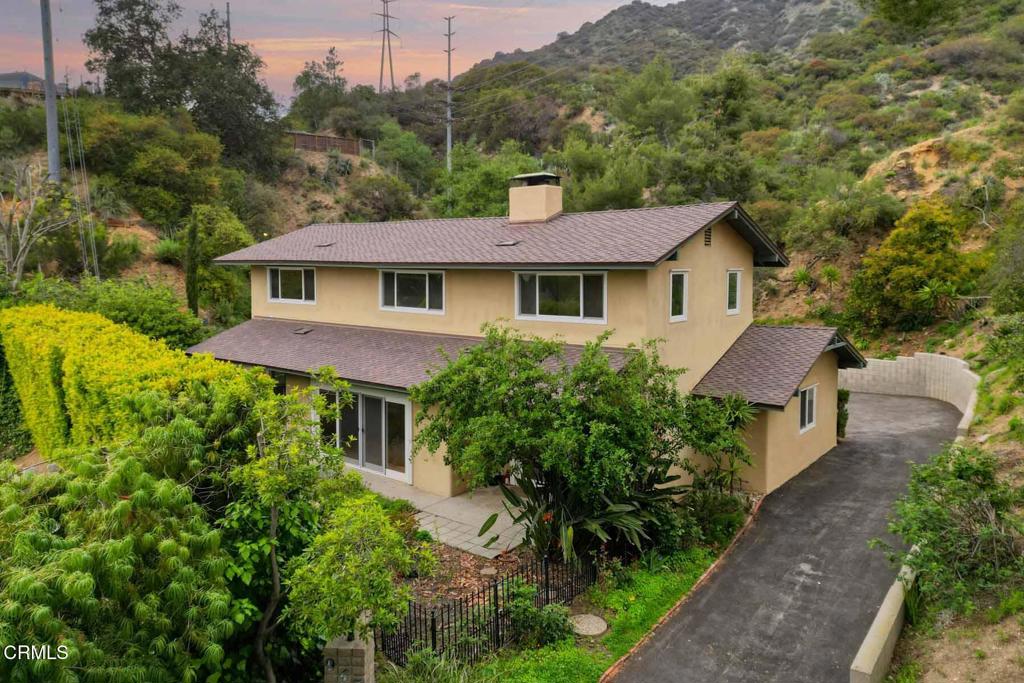 First time on the market in 23 years! This secluded, quiet home borders the Angeles National Forest with direct access to nature, hiking, and riding trails, yet is just minutes from downtown La Canada and major freeways, offering the perfect blend of mountain serenity and city convenience. Tastefully updated and well-maintained, this 4-bedroom, 3-bathroom home features refinished hardwood floors that extend throughout most of the home. There is a formal entry and spacious living room with a wood-burning fireplace that opens to the dining room. Both rooms have high ceilings and are filled with natural light from sliding glass doors that lead to water-efficient gardens, a patio, and a small waterfall--ideal for outdoor entertaining. The remodeled kitchen overlooks the rear yard and includes stainless steel appliances, a breakfast bar, dining nook, built-in desk, tile flooring, a walk-in pantry/laundry room, and direct access to the garage with a workshop, shelving, attic storage, and wired for Tesla charger. The main level also offers a cozy den with recessed lighting, wet bar, and high-efficiency wood stove to help heat the home, along with the 4th bedroom/home office and a nearby 3/4 bath via a short hallway for privacy. Upstairs, you will find a spacious primary suite with a walk-in closet and a newly remodeled bath. There are two additional bedrooms, a full bath with dual sinks, and a laundry closet with ample storage. The upstairs bedrooms overlook Angeles Crest Estates and offer a distant peekaboo view of the Southern California coastline, including Palos Verdes and Catalina. The rear yard is nestled against the natural amphitheater of the Angeles National Forest with a seasonal stream. It includes a large grassy area, a patio with a retractable awning, a chicken coop, and a garden with automated irrigation to grow healthy vegetables. The yard is filled with native wildflowers, various plants, and productive fruit trees, including avocado, kumquat, orange, lime, grapefruit, pear, and plum. The home is energy-efficient with dual-pane windows and doors, attic/wall insulation, passive solar design, south-facing orientation, and a GAF Cool Roof with a transferable lifetime warranty, all of which help lower energy bills. With fresh paint and carpet, a newer driveway, and the award-winning La Canada school district, this move-in-ready home is a rare find you'll love for years to come!