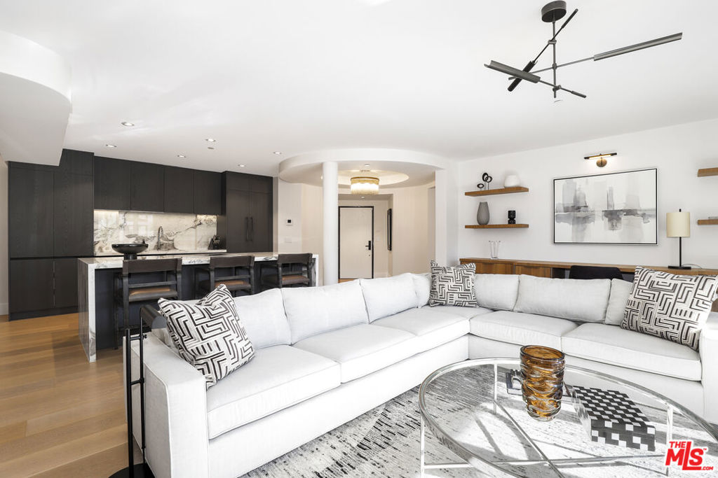An extraordinary residence in the heart of West Hollywood, this front-facing corner home redefines modern luxury. Exquisitely reimagined with the finest finishes, the 2-bedroom, 2.5-bath floor plan is bathed in natural light and framed by wide-plank wood floors, creating a seamless blend of sophistication and comfort. The grand living room, anchored by a sleek fireplace, opens to an expansive balcony, setting the stage for effortless indoor-outdoor living. A culinary masterpiece, the kitchen showcases Miele appliances, imported Italian marble countertops, integrated refrigeration, and bespoke custom cabinetry a space designed for both everyday living and entertaining at the highest level. The adjacent dining area, with its own private balcony, extends the home's sense of refinement. The primary suite is a sanctuary unto itself, featuring a custom-designed walk-in closet and a spa-inspired en suite bath with dual vanities, a soaking tub, and a glass-enclosed shower. The secondary bedroom offers its own private en suite retreat, perfect for guests or an elegant home office. Additional luxuries include an in-unit laundry, two secure parking spaces, and access to a spectacular rooftop deck with sweeping panoramic views of the city skyline. Just moments from the most coveted dining, boutiques, and nightlife West Hollywood has to offer, this one-of-a-kind residence epitomizes timeless elegance and contemporary sophistication.