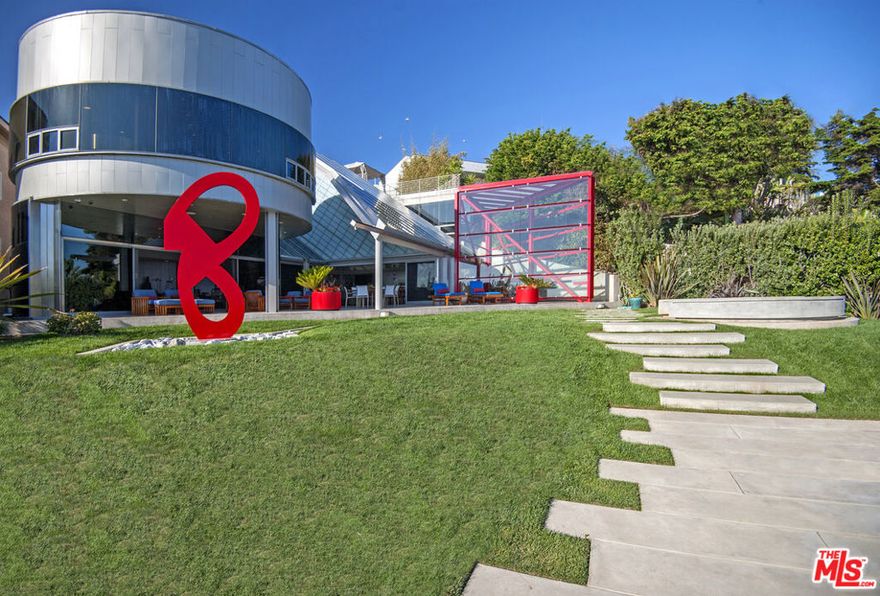 A masterpiece of modern design, this iconic beachfront estate was envisioned by world-renowned architect Ed Niles in collaboration with a celebrated structural engineer. A rare fusion of form and function, the residence is a bold yet graceful expression of light, geometry, and coastal serenity.Perched directly on the sand, the property offers unrivaled access to the Pacific Ocean while maintaining a level of total privacy and exclusivity rarely found on the Malibu coastline. Soaring translucent volumes, inspired by the ethereal beauty of shoji screens, invite the shifting light of the sea and sky into every corner of the home-framing breathtaking views and dissolving the line between interior and exterior.Beyond its striking aesthetic, the home was intentionally engineered to mitigate the impact of future natural disasters, including seismic activity and rising sea levels. Its robust concrete-and-steel construction not only offers exceptional resilience and fire resistance, but also stands as a proactive design response to the evolving demands of coastal living.Every element is aligned with the principles of harmony and balance, seamlessly integrating Feng Shui, natural airflow, and organic material expression into a home that feels both grounded and visionary.The main residence features four exquisite bedroom suites including a dramatic primary suite with curved glass walls and a detached guest house for added privacy. Designed for collectors, visionaries, and world-class entertainers, the property also includes a dedicated music room, soundproof theater, 19-server capacity, private generator, and elevator.This is more than a home it is a future-forward sanctuary, conceived for those who demand timeless design, structural integrity, and a deep connection to the elemental beauty of the ocean.