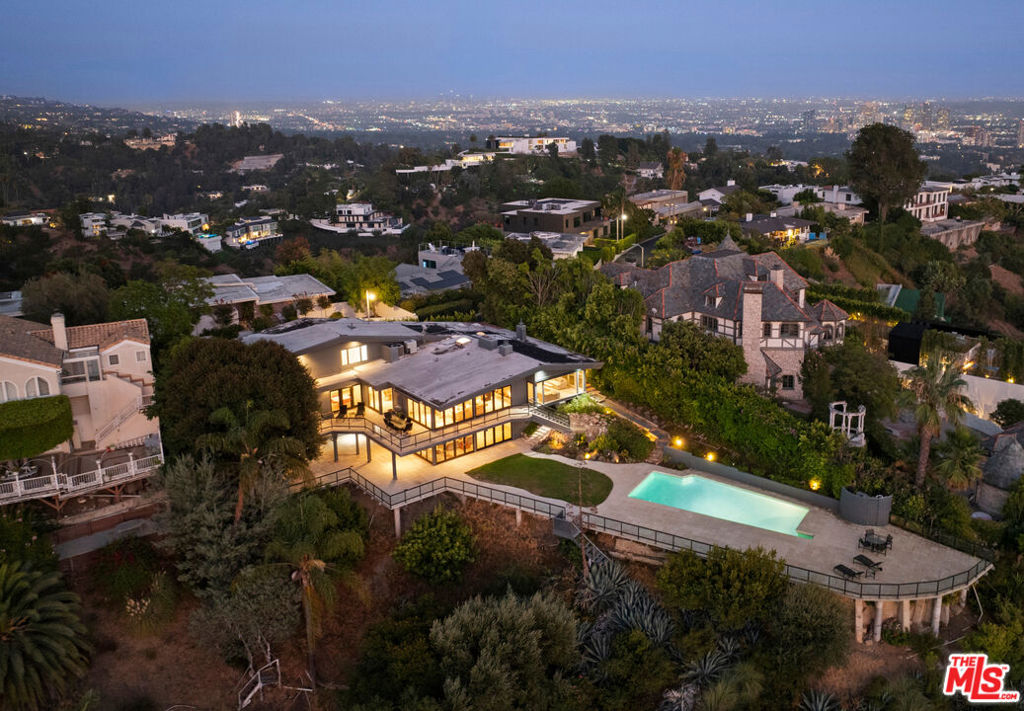 Experience the luxury of unobstructed panoramic views that span the city, canyons and ocean in this private, gated contemporary home with all the natural light, on one of Bel Air's most highly sought-after streets. A formal foyer unfolds into the sun drenched living room with floor to ceiling glass windows that flow seamlessly past a wraparound terrace to the horizon via the outstretched sun deck below, complete with lawn, landscaping and the prerequisite swimmers pool. A deceptively generous dining area connects the main lounge to a clean and crisp modern kitchen with island, breakfast area and professional grade appliances with deck access and those endless views. The expansive family room, with its own neatly tucked away wet bar, features a show stopping fireplace and the ultimate in indoor/outdoor living with access to that entertainers dream of a main deck just made for summer pool parties, morning coffee or sunset cocktails. Three of the four bedrooms share those breathtaking views, with the spacious primary suite encompassing its own fireplace, a beautifully lit custom walk in closet and a palatial marble bathroom. Note: Some rooms have been virtually staged.