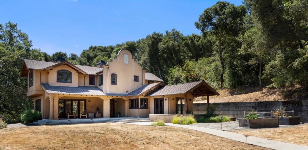 Privately positioned on approximately 1.85 acres with unobstructed views of Jasper Ridge Biological Preserve, this custom-built home offers a rare sense of serenity and seclusion just minutes from town. The setting is truly exceptional - vast, mostly level grounds bordered by open sky and native landscape. Designed for indoor/outdoor living, the home features an expansive flagstone terrace and covered front porch, along with a secluded rear terrace and spa - all surrounded by the natural beauty of Woodside and Portola Valley. A striking architectural presence is established with its signature shaped parapet, handcrafted detailing, and richly hued finishes inspired by classic Spanish Revival style. Inside, the warmth continues with red birch floors, wood-paneled cathedral ceilings, and hand-selected tilework from Walker Zanger. Every room captures the views, and the kitchen is appointed for serious cooking with premium appliances, a walk-in pantry with wine storage, and an open connection to the indoor/outdoor dining room. Moments from hiking and biking trails, top-rated schools, and local amenities, this is a home that lives like a country retreat yet remains just minutes from the heart of town and Highway 280.