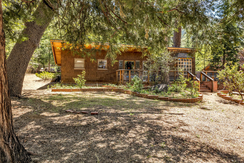 ORIGINAL AND UNSPOILED GEM. Beautifully maintained mid-century built home with clean angular lines complemented by an appealing open floor plan and expansive composite decking and patio areas providing multiple outdoor spaces for relaxing and enjoying the natural surroundings. Dramatic beamed ceilings and natural pine paneling highlight the charming interior with rock fireplace and classic finish details including custom built-ins. In addition to the spacious kitchen with hand crafted cabinets and original formica countertops, there is a light and bright dining room with multiple view windows, including a unique bay window with a modernist geometric grid pattern. There are 2 bedrooms and 1.75 baths, including a large dormitory size primary bedroom with bath and exterior access. Situated on a beautiful, near level 10,000+ square foot parcel in desirable Fern Valley, with Lily Rock views, a circular driveway and lots of parking. A new roof has just been installed along with some newly installed fencing. Selling furnished, including kitchenware.