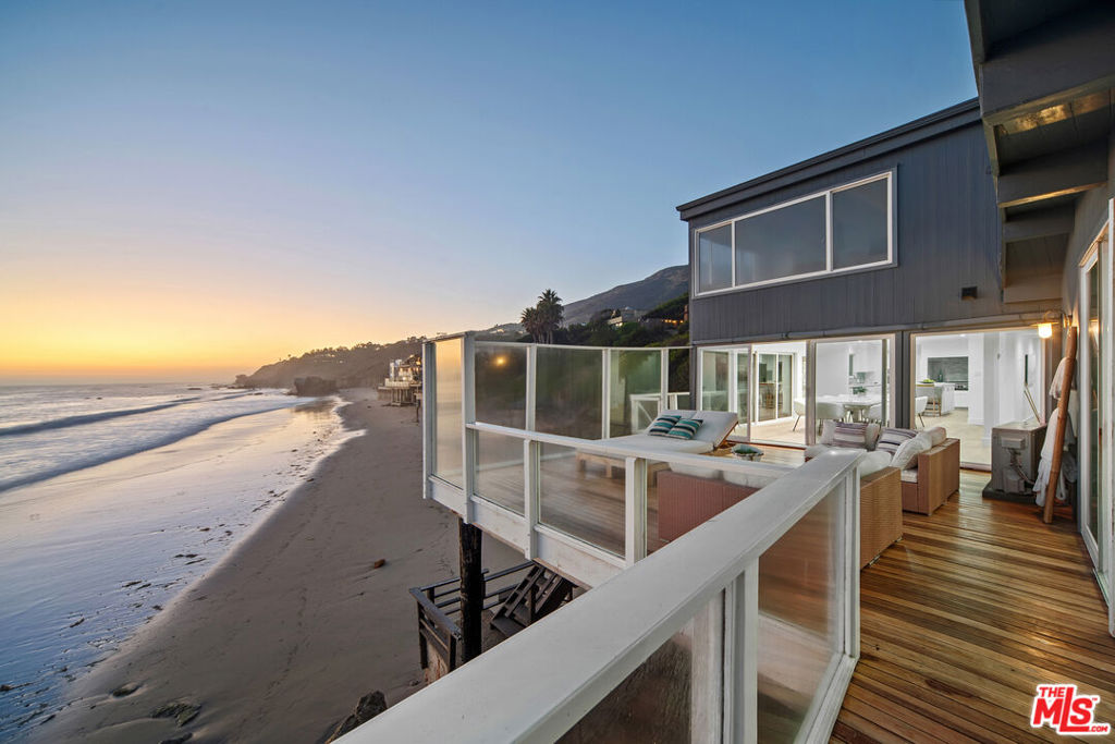 Sitting on a rocky outcropping where the waves of Matador Beach lap along the sand, this 2,861-square-foot, 4 bedroom 4.5 bathroom gem takes the experience of Malibu beach-front living to a new level. The interiors are a bastion of dazzling light and unobstructed coastline views of the sunset and the Channel Islands are incredible. A clean and contemporary design, where relaxation is paramount and vistas of the coveted serene surroundings take center stage. Recently renovated, the living spaces are remarkably open and bright, the corner dining room is wrapped in windows that create a veritable wall of dynamic, cinematic art capturing ocean waters, clear blue sky, from the Channel Islands and Point Dume in the distance, and further beyond, the definitive, far-reaching line of the horizon. The space flows directly to an open kitchen with an island, plentiful white cabinetry, new modern tile, refreshed countertops, and stainless-steel appliances. The nearby living room benefits from a similar expanse of glass with a dramatic view. The room's fireplace creates welcoming, comforting warmth on cooler days and nights. One of four bedrooms, the vast primary suite includes a sitting area, wall-sized picture windows, and sliding doors to a romantic private Juliet balcony. The en suite bath offers a generous dual-sink vanity, heated towel racks, a glass-enclosed rain shower, and a vintage-inspired soaking tub perfectly poised to appreciate horizon views. Two additional bedrooms and baths are secluded on the upper level as well, while a 4th bedroom suite is located on the main level. Large, ocean view decks and easy access to the beach below. The property's location, in a small exclusive enclave on a private gated road, puts it within a moment's reach of fine shops and restaurants and all the other allurements and enticements of Malibu, Vintage Grocers Market, at Trancas Cyn. and Zuma Beach.
