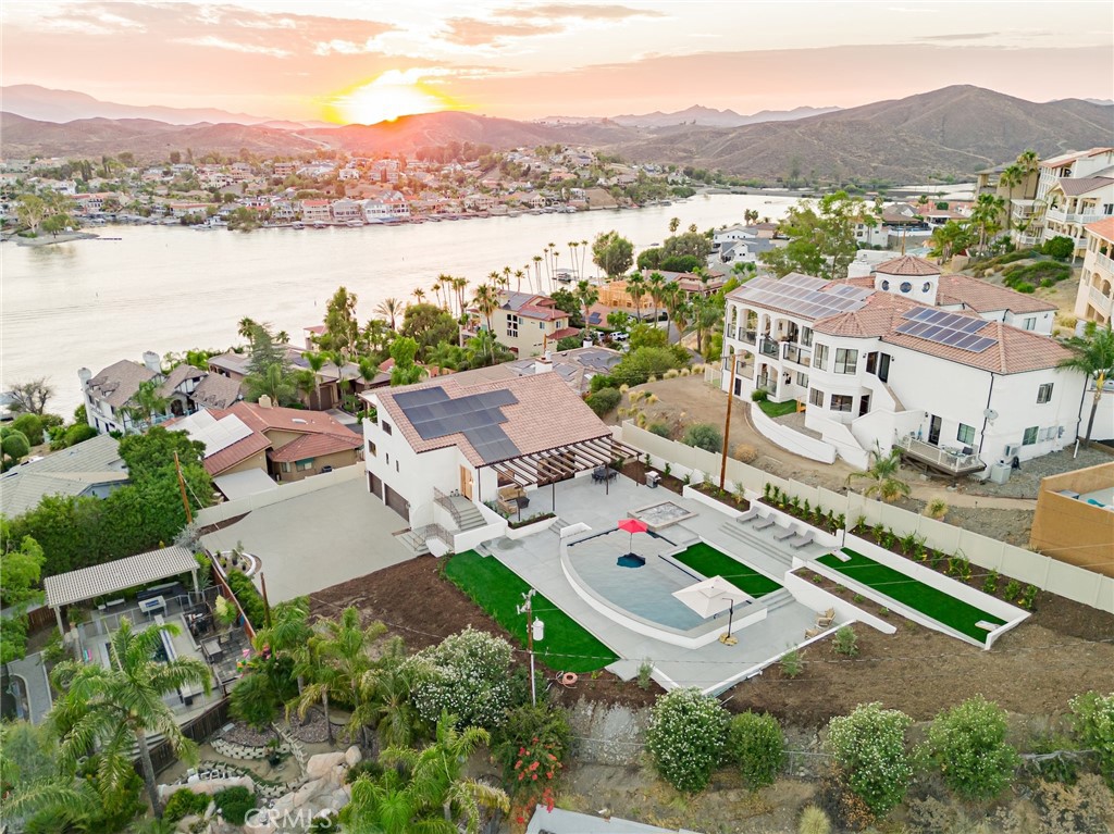 Imagine waking up every day to stunning lake views, where your backyard is an endless playground and neighbors feel like family. This incredible home has been completely remodeled and offers breathtaking, unobstructed lake views from nearly every corner...doing a stellar job at blending rustic charm with modern elegance. Sitting on nearly a 1/2 acre (18,731sf. lot) this home can meet all your parking needs with a brand new freshly poured 5,000sf driveway, a 3 car garage and plenty of room for an RV as well as a boat, multiple golf carts, several cars and all of your other toys! Step through the grand foyer as you enter through the brand new custom stained wood door, soaring vaulted ceilings with rustic beams, a charming half bathroom, and a striking staircase adorned with rustic stone and wrought iron railings leading to a perfect private exercise room/office. The 12-foot bi-fold door opens seamlessly to a sprawling 600 square-foot covered patio, perfect for entertaining with that popular indoor/outdoor feel. The heart of the home is the wide-open kitchen, boasting wall-to-wall lake views on the west side, a massive kitchen island ideal for gatherings, custom rood, tons of counter space and a large walk-in pantry for all your culinary needs. Adjacent, the TV room, affectionately called "The Chapel," features a vaulted ceiling with custom rustic wood beams, large stone hearth fireplace and a double slider to a private balcony with wild, unobstructed lake views with killer sunsets almost every single night. Retreat to the two-level master suite, a true sanctuary. The first level offers a spectacular brand new master bathroom and a spacious walk-in closet, while the second level features a private master bedroom suite with its own half bath and a spacious private covered balcony showcasing nearly 180-degree lake views! A custom storage room off the master ensures all your storage needs are met. Saving the best for last, the brand spanking new 30,000-gallon resort style pool and spa provide a luxurious escape with stunning lake views, complemented by 3 artificial turf areas, entire brand new pool fence and a perfect place to drop in an outdoor living/cooking area next to 5 sunken bar stools. The expansive backyard is an endless playground, offering space for relaxation and recreation. This Canyon Lake gem combines unparalleled luxury, thoughtful design and a prime location high above the lake with irresistible views. This is more than a home—it’s a lifestyle.