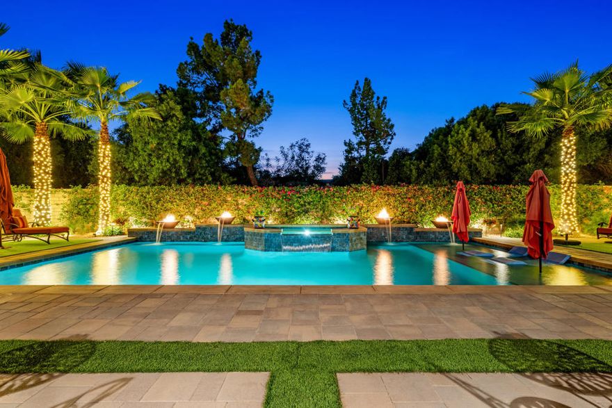 Experience resort-style living in this exquisitely upgraded 4 bed 3.5 bath 2,911 SF home with a private casita on a 1/4-acre lot--where sophistication meets comfort. Enter through a custom front gate and glass door to soaring ceilings and sunlit spaces that flow seamlessly from the grand entry to the den and formal dining room. The open-concept living area boasts a custom entertainment center and modern fireplace, framed by new flooring, baseboards, and elegant crown molding throughout.The gourmet kitchen features granite counters, a chic LED-lit backsplash, pull-out cabinets, soft-close drawers, a walk-in pantry and a spacious eat-in island with breakfast nook. Down the hall are two generous guest rooms, while the casita offers its own entrance and the lavish primary suite overlooks the newly landscaped backyard retreat.Step outside to your custom designed luxurious oasis--complete with a covered outdoor kitchen and bar, lush landscaping with palms, pavers & vibrant turf, and a resort-style pool accented by fire-and-ice bowls and a custom fire pit. Every detail, from the high-tech security and misting system to the refined finishes, creates a sanctuary of luxury, technology and timeless beauty within the gated community of Carmela. This home is move-in ready & ready to impress.