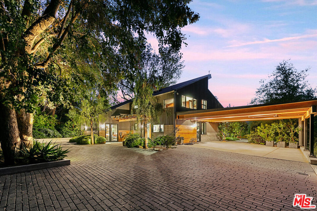 Nestled on two gently sloping acres studded with majestic oaks and fragrant eucalyptus, this fully reimagined Topanga estate offers a rare blend of refined luxury, privacy, and natural beauty. Designed for both connection and independence, the property features multiple living spaces thoughtfully integrated into the landscape with a system of winding paths, orchards, and curated gardens. At the upper end of the property, the main residence showcases sleek contemporary finishes, expansive glass doors, and a seamless indoor-outdoor flow, ideal for entertaining or a quiet retreat. The resort-style pool is surrounded by fruit trees and curated landscaping, creating a tranquil, sun-soaked oasis with sweeping sunset and canyon views. At the opposite end of the property, down a meandering path lies a beautifully appointed guest house with its own private outdoor entertaining area, offering comfort and autonomy for family, friends, or creative pursuits. Situated on the same end of the property is a custom-renovated Spartan trailer that offers a unique living experience, complete with a private outdoor bath and lounge area set under the stars, an ideal retreat or artist's haven. A newly constructed workshop or recording/art studio at the lower edge of the property serves as an additional flexible space for work, storage, or accessory living quarters, enhancing the estate's versatility. The distance between structures affords a rare level of autonomy with the lower buildings and vintage (1950) trailer able to be accessed through a separate (service) entrance, while still maintaining a strong sense of cohesion through thoughtful design and landscaping. A quiet safe haven, a true compound with state park and miles of mountain biking and hiking trails out your front door. No driving needed. This is Topanga at its most inspired "Paradise Lodge", a private sanctuary where luxury meets nature and every detail is crafted for elevated, intentional living.