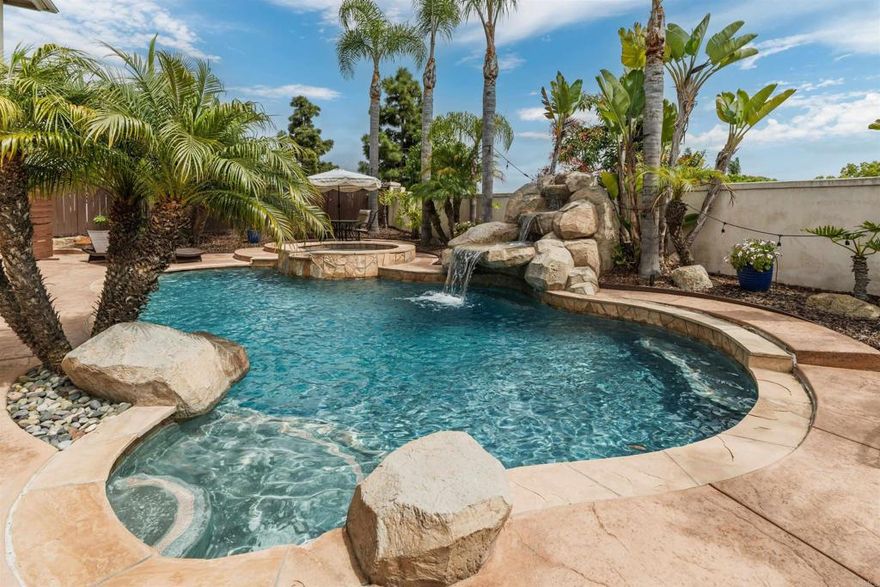 Located on a quiet cul-de-sac in the highly sought-after Viadana community, this expansive Carlsbad home pairs laid-back luxury with everyday comfort—offering over 3,300 square feet of thoughtfully designed living space. The flexible floor plan is ideal for modern living, with a main-level guest suite and adjacent bath, a private home office with French doors and a walk-in closet, and seamless indoor-outdoor flow that makes entertaining feel effortless. Just minutes from top-rated Carlsbad schools, scenic trails, and North County’s most loved beaches and golf courses, this home offers a lifestyle that feels both convenient and effortlessly relaxed. A gated front courtyard creates an inviting first impression, opening to a bright and airy interior finished in a soft neutral palette. The formal living room welcomes you with two walls of windows, while the adjacent dining room impresses with soaring ceilings and a dramatic rotunda layout that brings architectural interest and a sense of openness. Just across the hall, the home office offers flexibility—with French doors that open to the courtyard, the dining area, and the back hallway, it’s easy to imagine it as a creative studio, quiet retreat, or potential sixth bedroom. At the heart of the home, the open-concept kitchen and family room are made for connection. Granite counters, a built-in fridge, gas range, double ovens, and an oversized island provide space to prep and gather, while the generous cabinetry space keeps everything organized behind the scenes. Large windows overlook the backyard and create a natural connection between the interior and your own private outdoor retreat. Upstairs, the rotunda landing leads to a serene primary suite with a spacious ensuite bath, complete with dual sinks, a makeup vanity, soaking tub, walk-in shower, and a large walk-in closet. Two additional bedrooms share a full bath with dual sinks, and a nearby laundry room with sink and linen storage keeps things practical. A spacious loft opens to a breezy balcony, while an adjoining bonus room—complete with wet bar and built-ins—makes the perfect media room, home gym, or flex space for your evolving needs. Step outside and you’re instantly transported. A sparkling saltwater pool with a large tropical waterfall, a relaxing spa, and lush landscaping framed by mature palms create a resort-like vibe. The built-in outdoor kitchen with bar seating makes entertaining a breeze, while multiple seating areas invite you to unwind. Additional upgrades include solar (installed 2023), air conditioning, EV charger, whole house fan, smart security system with Ring doorbell, and automated irrigation and lighting. There’s even a first-floor storage closet to keep everything out of sight but within easy reach. All this just minutes from top-rated Aviara Oaks Elementary and Middle Schools, the Batiquitos Lagoon trails, Dove Library, local shops and restaurants, and some of North County’s most iconic beaches and golf courses. Whether you’re starting your day with a quiet coffee in the courtyard or ending it with a dip in the pool, this home invites you to slow down and enjoy the best of coastal California living.