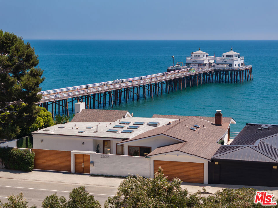Introducing a rare double-lot beachfront sanctuary with 74 of ocean frontage on Malibu's coveted Surfrider Beach. This single-story coastal retreat blends sweeping ocean views with architectural grace. A gated arrival reveals a motor court with parking for multiple vehicles and a private garage.Inside, the expansive living and dining pavilion features vaulted ceilings, hardwood floors, a fireplace, and three oversized ocean-facing windows framing panoramic vistas including the iconic Malibu Pier. This space flows seamlessly onto a wraparound porcelain-tiled oceanfront deck, perfect for indoor-outdoor entertaining.The gourmet kitchen offers a granite island, skylights, Sub-Zero and Thermador appliances, and captivating ocean views.The primary suite delivers ultimate privacy and luxury with a marble fireplace, glass sliders opening directly to the deck with Malibu Pier panorama, an oversized custom closet, and a spa-like bathroom with steam shower, soaking tub and heated floors. Three additional bedrooms, two ensuite with sunset deck access, provide stylish accommodations for family and guests.Modern upgrades include a whole-house generator, EV charger, Sonos system, and porcelain flooring throughout the primary suite and deck. With proven rental history, (partial seawall protection), and a premier location near Nobu, Soho House, and Malibu Country Mart, this refined oceanfront estate offers rare scale, prestige, and iconic Malibu Pier views.