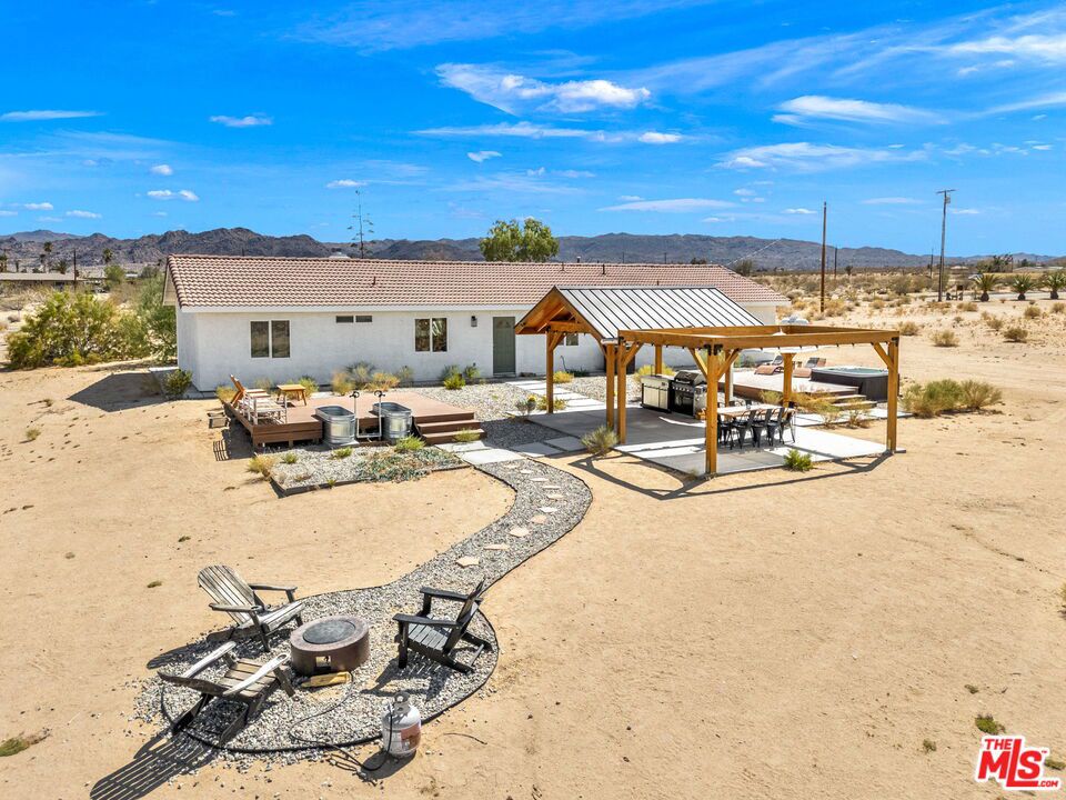At the end of a fully paved road sits this 1,872 sq.ft. 3BD/2BA, fully furnished and recently remodeled Joshua Tree home. From either the front door or the direct access from the garage, one is greeted by a large open living space. Just off the dining area is the separate kitchen area with newer stainless-steel appliances and a large window to take in the mountain views. On one side of the home is the primary suite with a walk in closet and private bathroom. The other side of the home is rounded out by two additional bedrooms and a full-size bathroom. Step outside to the back where various entertainment hubs are aplenty. Enjoy gourmet meals from the built-in BBQ area under the gazebo. A hot tub and cold plunge baths provide aquatic activities in all climates. Finally, if you are looking to just relax, one can swing in the breeze on a hammock or get cozy around the firepit. Property has been used as a STR, and financials are available. Sitting on over two (2) acres of land, this home is perfect for those looking to balance privacy with easy access to the town's amenities. NOTE: For paved road access, please use Sunfair Road for access to Broadway. DO NOT use Sunburst Avenue.