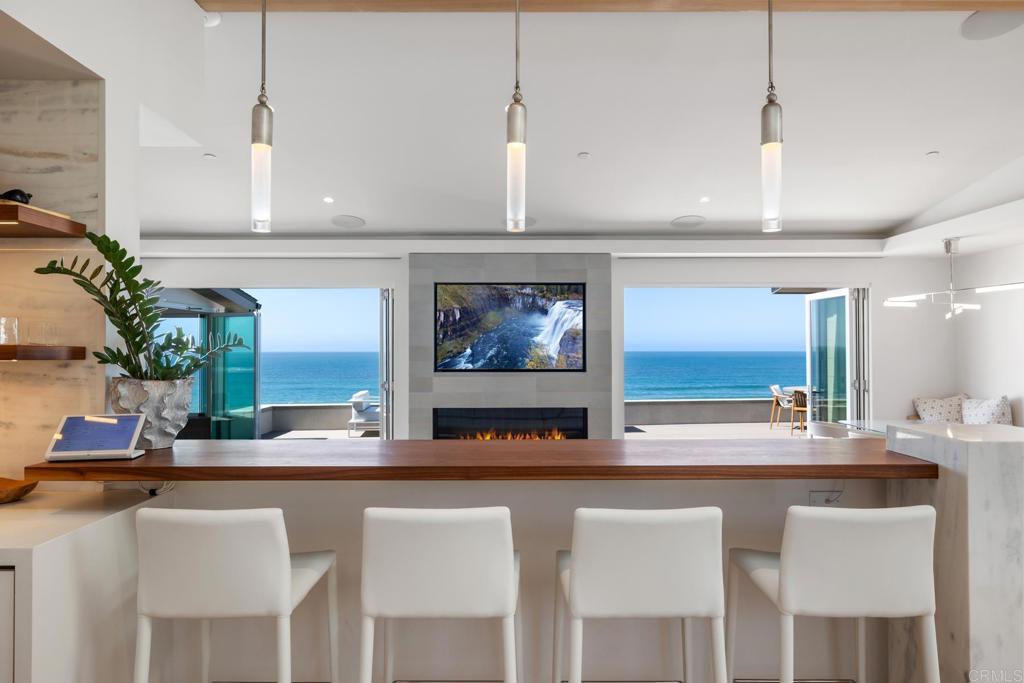 Steps from Moonlight Beach, nestled atop a private drive and concealed behind an automatic gate you will find without a doubt, our favorite ocean front home EVER in Encinitas. 100 Fifth Street redefines the luxury of coastal living. A recent multi-million dollar renovation and over 1,600 square feet of combined lanai and covered patio space elevate this property to a once-in-a-lifetime escape. Situated on over a quarter acre of land and with over 100 feet of ocean frontage and a path down to the sand, the property offers something no others in Encinitas can or ever will. Exquisitely crafted to bring luxury to your every day, the kitchen overlooks a stunning view and absolutely no detail. The Meile suite of appliances, custom cabinets and marble backsplash come together flawlessly to create a spectacular level of understated elegance. The single story living and open-flow layout invites friends and family to pull up a chair, grab a cocktail and enjoy the sun disappear into the ocean
