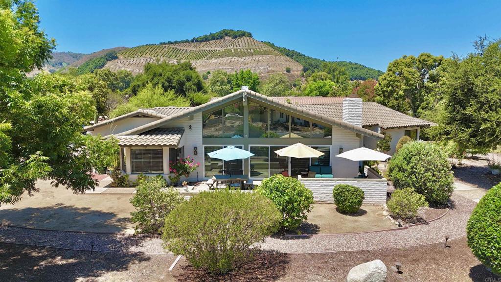 Mid-Century Magic Meets Modern Living! Talk about location, location, location! This gorgeous single-story gem sits at the end of a quiet cul-de-sac with incredible Palomar Mountain views that'll have you sipping your morning coffee in pure bliss. Not to mention, that front door? It's a total showstopper - the original builder knew what they were doing! The primary suite features an oversized mid-century shower and the home has fresh updates where it counts: newer slider doors, appliances, roof, AC, whole house ducting and more. The fully fenced backyard is your own private oasis complete with established garden boxes, fruit trees scattered around the property (the peaches are ripe today), and is also perfect for your furry friend(s)! It is a spacious double lot that gives you room to breathe (and maybe add that ADU you've been dreaming about - it's state approved!). The home is literally across from the 17th fairway of Pauma Valley Country Club. Morning tee times optional, but the views are mandatory! Bonus perks: massive 2+ car garage with storage for days, and here's the kicker: while the title shows 3 bedrooms, the seller never enclosed the third one, so you've got flexibility to make it whatever you need. Ready to live your best mid-century modern life? Let's talk!