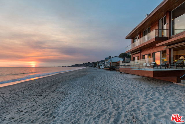 Located on one of the most exclusive enclaves in the world, this two-story Carbon Beach home, with 60' of sandy beach frontage, offers the ultimate Malibu lifestyle. Private and gated with a beautiful landscaped courtyard entry, BBQ island & access to the sandy beach, the main level includes an ocean view, high wood ceiling great room with fireplace living room, dining area, additional sitting room with custom bar & a gourmet island kitchen, all with ocean views through walls of glass sliders that open to an expansive entertaining/viewing deck with outdoor shower & spectacular Catalina, whitewater & panoramic coastline views. The entire second floor, with skylight landing, offers a generous sun-filled master retreat with high wood ceilings, separate sitting area or gym & a luxurious bath with spa tub, glass shower & endless ocean views. There are three en-suite bedrooms on the main level, detached garage and guest parking. Close to restaurants, shops, organic grocery & downtown Malibu.