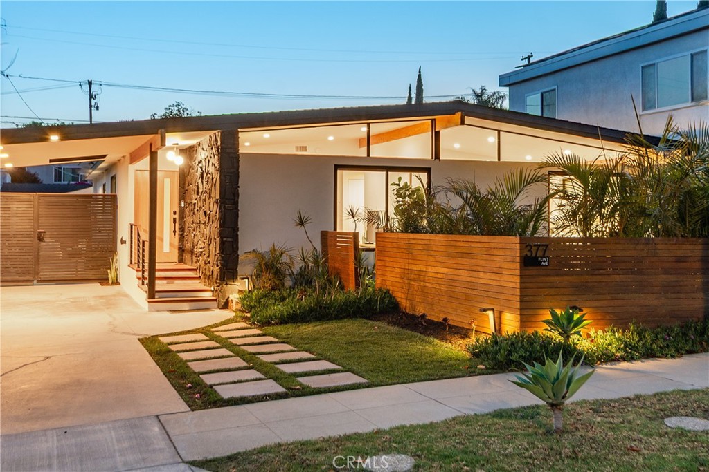 CUSTOM MID-CENTURY MODERN BY THE BAY Introducing 377 Flint Avenue, custom Alamitos Heights mid-century modern pool home on a wide, oversized lot. Rare opportunity to experience exceptional architectural design in an A+ interior location. Desirable beach close community of tree-lined streets and just moments to the Bay. Large lot with long gated driveway offering crowd pleasing curb appeal with mid-century modern elements. Gorgeous landscape and hardscape with private grassy courtyard. Generous use of windows bring the outdoors in with a focus on indoor/outdoor living. Formal entry to stunning living room space. Open concept kitchen/family room with 11 ft Windsor folding doors with beautiful pool views. Sunny kitchen opens to the family room with center island and stainless appliances. En-suite primary suite has sliders to the private courtyard. Two additional bedrooms, one currently with additional home office space. Two beautifully updated bathrooms. Designer elements throughout including hardwood floors, Milgard windows, recessed mood lighting, smart home features, A/C, EV charging capability, and solar panels. Sparkling pool is a focal point of the backyard along with multiple patio spaces, outdoor kitchen, lanai, and two car garage offering additional flex space. In addition to the long gated driveway, two car garage, and porte cochere, there is also alley access allowing for additional versatility. Located in the sought-after Alamitos Heights neighborhood, you'll be just minutes away from local farmers' markets, outdoor concerts in the park, and Marine Stadium. With Long Beach preparing to host the 2028 Summer Olympics, this location is set to become even more vibrant and desirable. Excellent schools complete this exceptional opportunity.