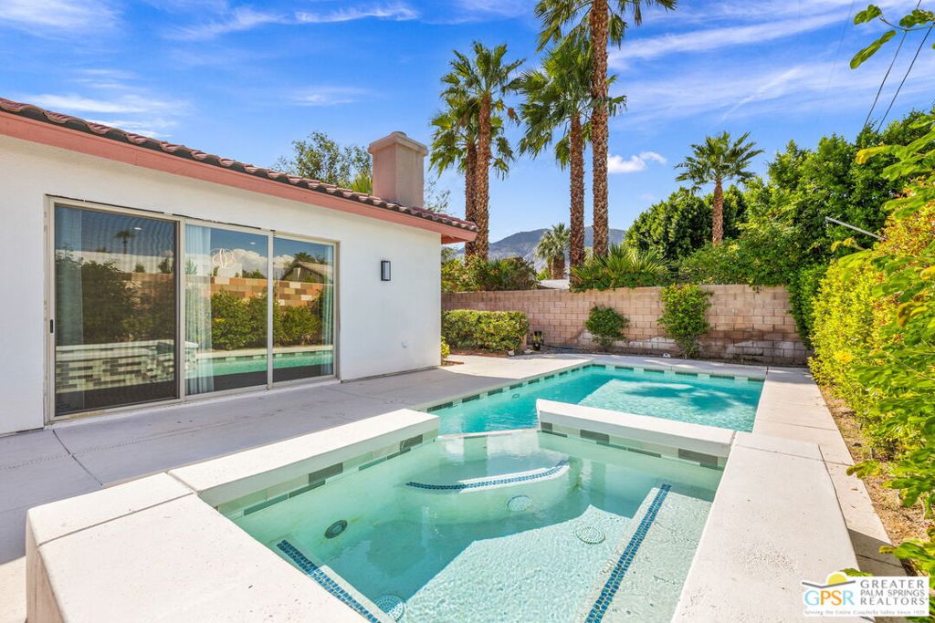 Contemporary open-concept Palm Springs pool home showcasing rare 2003 construction in Desert Park Estates. This exceptionally light filled and private residence with 8-foot doors and soaring 10-foot ceilings throughout is a beautiful example of Palm Springs living: stylish, comfortable, and inviting.The property is fully walled for privacy, and once you step through the front gate, you're transported to your own private oasis. The large front courtyard and backyard pool and spa area with newly tiled surfaces, offer multiple spaces for lounging, relaxing, and entertaining, all complemented by a freshly painted exterior. Redesigned desert landscaping provides water efficiency while maintaining a sizable patch of grass for greenery and enjoyment. A tall privacy hedge at the front creates an additional courtyard living area that's ideal for outdoor entertaining.At the heart of the home, the expansive great room features a beautiful fireplace, soaring ceilings, and a triple panel of glass sliders that open to the pool and raised spa. The open-concept layout includes distinct, well-planned living, dining, and kitchen areas, with the kitchen offering tiled counters, a breakfast bar, and a large pantry.Inside, the home is light and bright, enhanced by fresh interior paint that highlights the open design and generous natural light throughout. The spacious primary suite features a beautifully appointed bathroom with dual sinks, a step-in tiled shower, a stand-alone soaking tub, and a walk-in closet with a large picture window framing views of the lush backyard. A second patio off the primary suite provides a private lawn area perfect for pets. The suite is joined by a guest bedroom, a third bedroom, and a newly constructed fourth bedroom ideal for an office or den.Additional highlights include 2.5 bathrooms, a separate laundry room, and an attached air-conditioned three-car garage with a split unit. Your energy costs are kept low with 14 owned and 34 leased solar panels at $203 per month. Thoughtfully oriented to capture mountain views, this home offers ideal spaces for both sun and shade. A truly happy and comfortable residence designed for serenity, privacy, and effortless Palm Springs living. Your desert oasis awaits!
