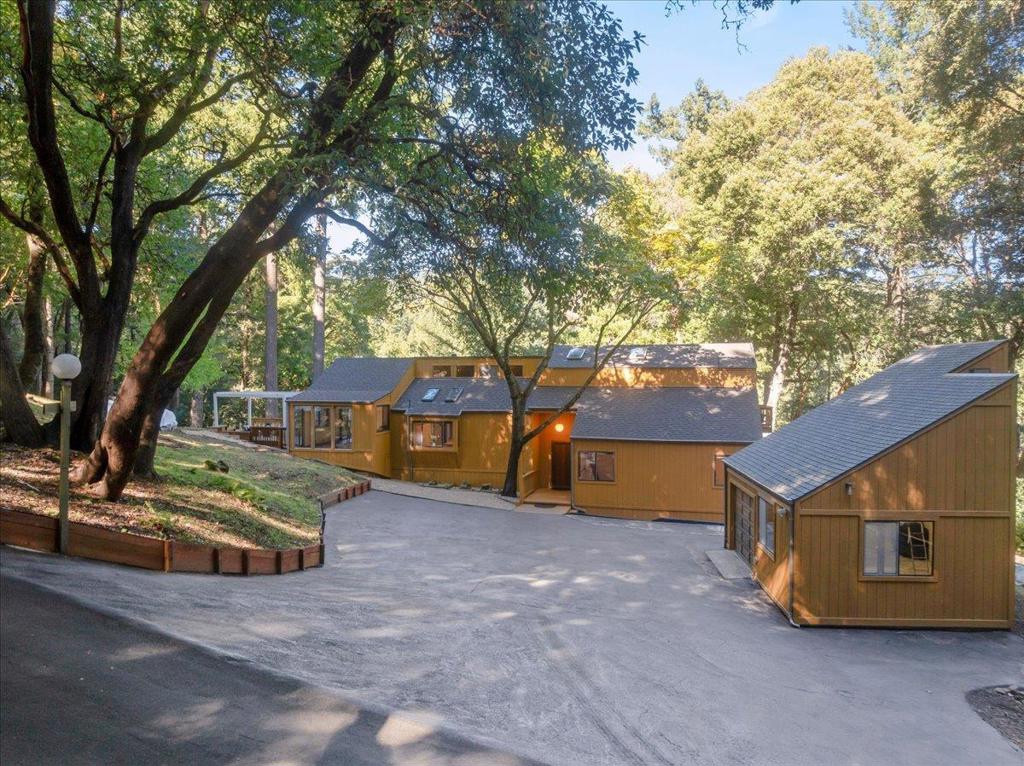 Escape to tranquility in this stunning home nestled in the forest of the sought-after Las Cumbres community. Dappled in natural light through soaring skylights and surrounded by nature, this unique home offers a seamless blend of rustic charm and modern comfort. Step inside to discover vaulted ceilings, and an open-concept layout with multiple lofts, designed for relaxation and entertaining. The kitchen features a bay window breakfast bar, perfect for morning coffee, and flows effortlessly into the dining room and dramatic wraparound glass entertaining nook invites the outdoors in, showcasing spectacular cross-canyon views. Enjoy the ultimate in outdoor living with numerous decks, ideal for gatherings, stargazing, or soaking in the hot tub under the forest canopy. A detached garage with loft and workshop provides ample space for hobbies or a creative studio. On the grounds, you'll even find an ancient Indian grinding stone, connecting this serene setting to the regions rich history where light, space, and serenity come together in perfect harmony. Las Cumbres community residents enjoy a vibrant lifestyle with tennis and basketball courts, a sports field, swimming pool, bocce ball, community BBQ area, and playground. High-speed internet, award-winning Los Gatos High School.