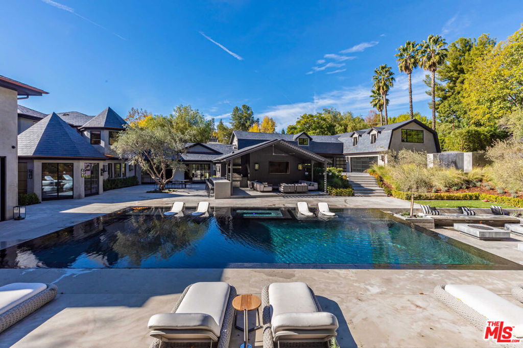 This gorgeous estate has been superbly rebuilt into a unique showcase of quality and true luxury living. Recently completed, and beautifully finished throughout, the wide-open floor plan features high volume ceilings, sliding walls of glass, and huge picture windows that flood the home with natural light. Amenities include a stellar chef's kitchen complete with built-in Espresso machine, opening to the spacious family room with fireplace, adjoining game room, custom theater, formal living & dining rooms, private study, mirrored gym & spa with steam shower & sauna, and 6 bedrooms (in main house), including the sumptuous master suite with fireplace and all stone bath. Amenities include steel & glass windows & doors, wood & stone floors, and unique custom lighting fixtures. The lushly landscaped and very private grounds include a big guest house, large zero edge pool & spa with lighted waterfall, sports court, deluxe covered barbecue center complete with space heaters and T.V.