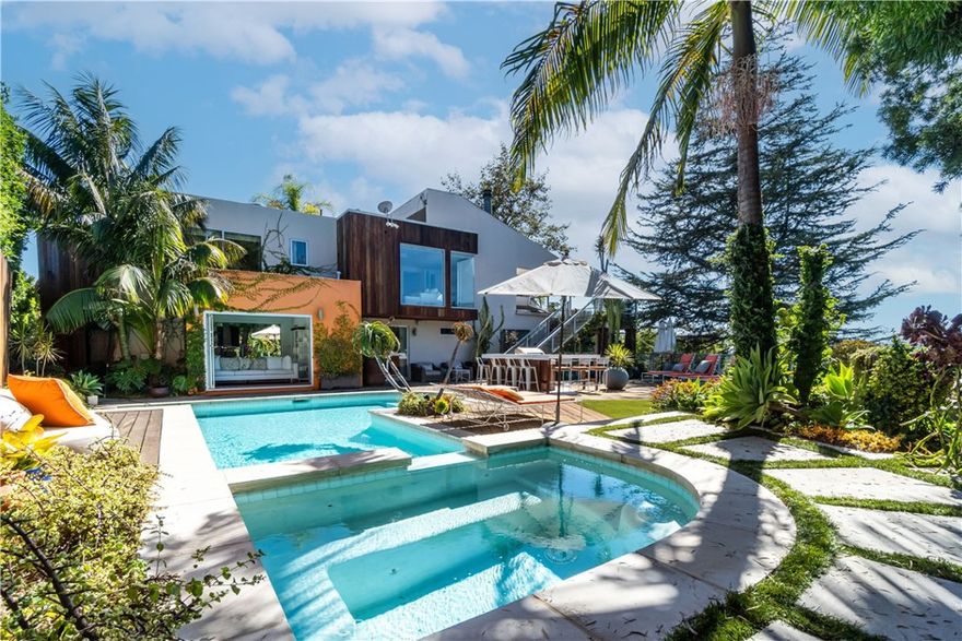 Secluded down a 100-foot driveway, this gated estate offers expansive ocean and canyon views with unmatched privacy. The main level features three bedrooms, including a stunning primary suite that opens to resort-style grounds with pool, spa, cabana, outdoor kitchen, fire-pit, and lawn. Upstairs, an open living and dining area flows into a gourmet kitchen with designer appliances, plus a guest suite with separate entrance and a den/office. Sliding glass doors lead to a large deck with al fresco dining, fireplace, and lounge seating—perfect for enjoying sunset views.