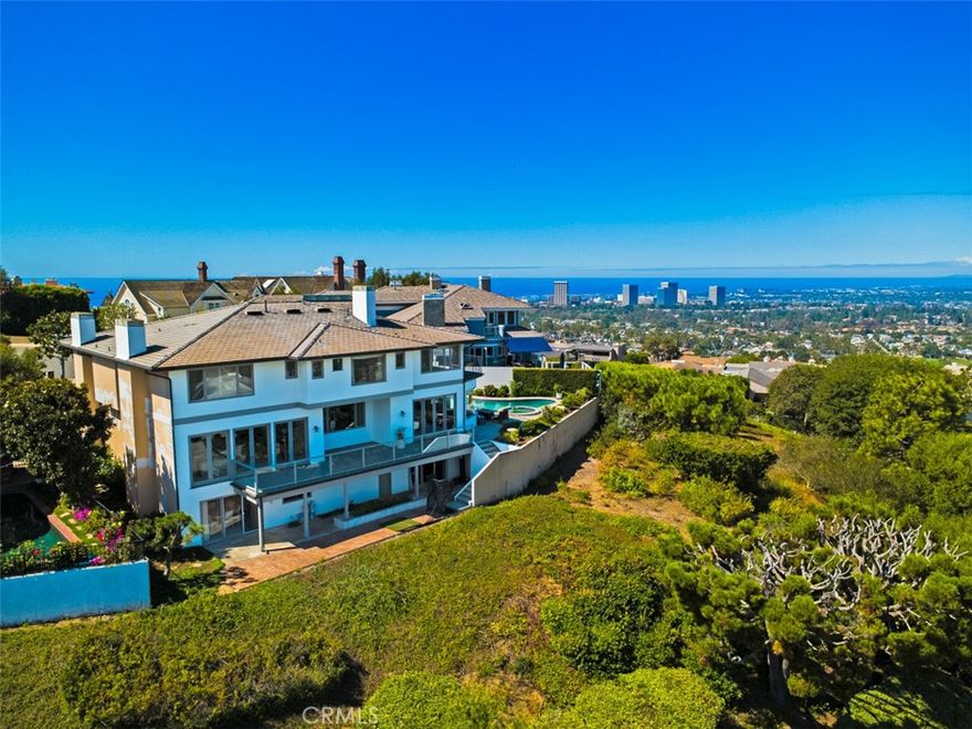 At the end of a quiet cul-de-sac, 17 Napoli offers one of those rare Newport Beach opportunities that don’t come around often. Set on an extraordinary 9,600 sq. ft. pie-shaped lot, this residence spreads its wings with privacy, space, and sweeping views that stretch across the city, mountains, and beyond. Spanning 7,844 square feet with 5 bedrooms and 8 bathrooms, this custom-built home is brimming with character and possibility. Inside, a grand curved staircase sets a tone of timeless elegance, while spacious living and entertaining areas are framed by walls of glass that showcase the property’s expansive wide-angle views. The home’s interiors are rich with personality—from a stately wood-paneled office with a fireplace, to a dramatic living room anchored by a marble statement fireplace, and a cozy den wrapped in warm wood and stone that spills seamlessly to the pool terrace. The kitchen, complete with a generous island, granite counters, and dark wood cabinetry, flows into a sunlit breakfast nook with panoramic vistas—where every meal comes with a view. Wine enthusiasts will delight in the brick-arched wine cellar, while entertainers will fall in love with the resort-style backyard, where a sparkling pool and spa glisten under California skies. Multiple outdoor terraces and patios invite morning coffee, sunset dinners, and evenings of stargazing. With generous square footage, custom details, and endless potential, this home represents not just a place to live, but a chance to create your dream lifestyle in one of Newport Beach’s most desirable neighborhoods. Whether you envision refreshing its classic charm or reimagining it with modern flair, 17 Napoli offers a fantastic value and rare opportunity to plant roots in an exclusive coastal enclave.