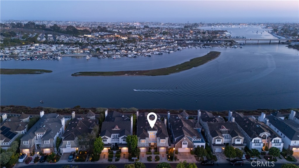 Perched blufftop, front row center in the coveted guard-gated Castaways community, this stunning Cape Cod-style residence showcases breathtaking, unobstructed vistas of the harbor, bay, Pacific Ocean, Catalina Island, city lights, and back bay. Behind a timeless coastal façade, a grand two-story entry welcomes guests with soaring ceilings, a dramatic staircase, and an open-concept layout designed to frame the views at every turn.
The sunlit great room flows seamlessly into the formal dining area and a chef’s kitchen outfitted with professional-grade Viking appliances, custom cabinetry, quartz countertops, a large center island with 6-burner cooktop, and a built-in breakfast nook. Designed for effortless indoor-outdoor living, the entertainer’s backyard features a PebbleTec saltwater pool, elevated spa with waterfall, firepit, built-in BBQ, and expansive stone patio—all set against a striking ocean backdrop.
Upstairs, the spacious primary suite captures panoramic ocean views and offers a cozy fireplace, private view deck, and a spa-inspired bath with free-standing tub, double-headed Carrara marble shower, dual vanities, and custom walk-in closet. Two additional upstairs guest bedrooms share a jack-and-jill bath and a versatile den can easily serve as a fourth bedroom. An adjacent loft office provides the ideal work-from-home space with tasteful built-ins and captivating water views.
Additional highlights include an elevator, three fireplaces, newer wide-plank oak flooring, epoxy-coated garage floors with built-in cabinetry, and a brick-accented driveway. With direct access to scenic hiking and biking trails and just minutes from world-class beaches, shopping, and dining, this home embodies the best of Newport living.