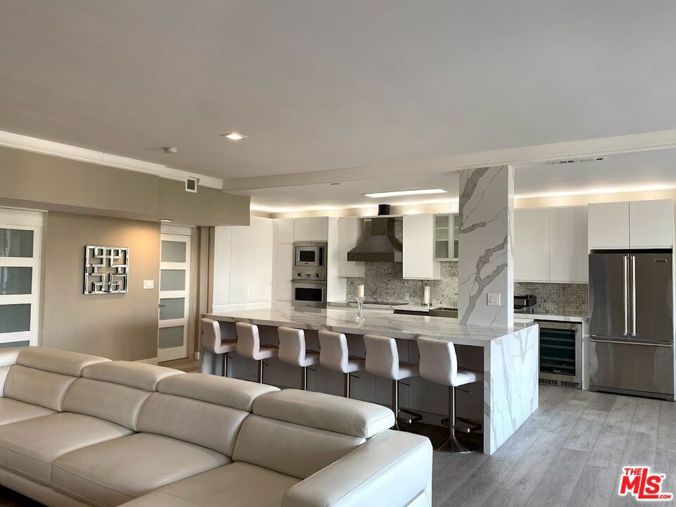 Discover urban luxury in this fully furnished contemporary oasis, showcasing a striking blend of modern design and chic finishes. Perfectly located near Westwood Village and Century City, this condo has been remodeled from top to bottom. The open-concept living space is ideal for both everyday comfort and grand entertaining, with high ceilings that amplify its airy ambiance. The kitchen is a showstopper, featuring Viking appliances, quartz countertops, super high-gloss white cabinets, and an island that comfortably seats six. A spacious L-shaped white leather couch anchors the living area, perfectly positioned to enjoy the 85-inch Smart Sony TV while taking in the city views. Floor-to-ceiling sliding glass doors open to a large balcony illuminated by sleek LED lighting, offering a dramatic evening backdrop. The primary bedroom includes a generous walk-in closet, and there is ample storage throughout, including hallway closets, a well-appointed laundry room with cabinetry, and additional closets in the powder room. A dedicated office area occupies a bright, open corner of the living space, offering its own city view and a vantage point to see the living room, kitchen, and TV - a perfect spot for both work and leisure. This full-service building provides 24/7/365 valet parking and security. If you're seeking luxury, location, and modern style in a full-service high-rise, this is your condo. Schedule a private showing today to experience it for yourself. Listed price is for 12 month term.
