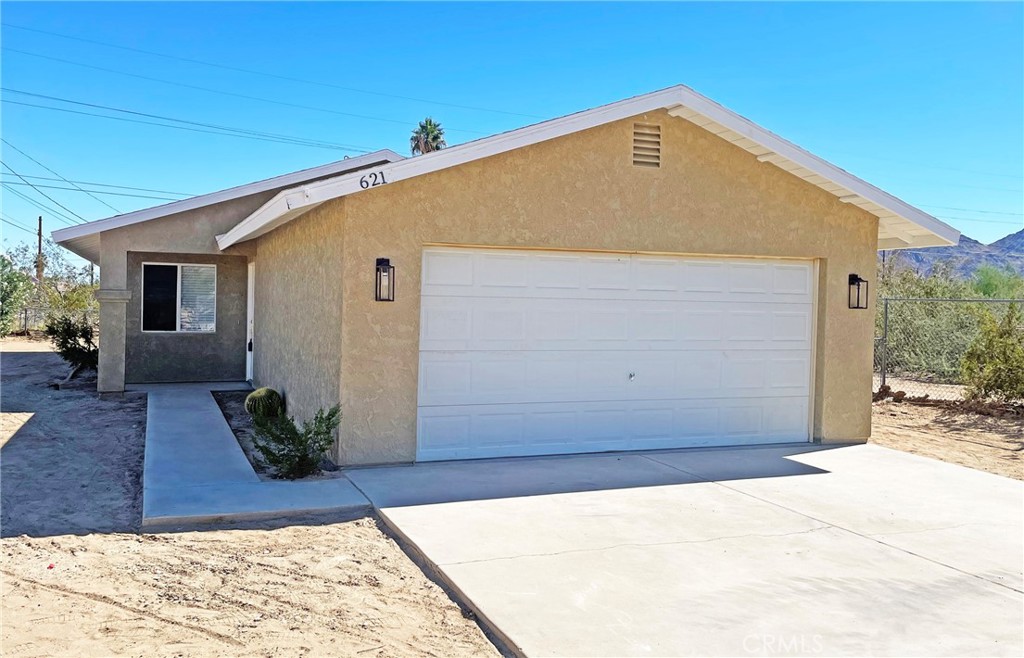 Fresh, Thoughtful Upgrades Throughout. 
This refreshed desert-style home features 3 bedrooms, 2 bathrooms, and about 1,248 square feet of upgraded, light-filled living space. Perched near Joshua Tree National Park and located close to the Chocolate Drop area, this home captures the soulful beauty of high-desert living. Step across gorgeous new flooring that flows from room to room, uniting the interior with modern elegance and ease of care. New blinds add clean, adjustable light control and privacy, balancing bright desert sunshine with serene interiors. The interior has been freshly painted in neutral tones, offering a calm, clean, and timeless backdrop that enhances the bright, airy feel. Throughout the home, new ceiling fans have been installed — stylish, efficient, and helping to circulate air for comfortable living during warm desert days and nights. Brand-new closet doors bring upgraded organization and storage to everyday life. In the heart of the home, the kitchen is elevated by a warm, character-rich butcher block counter-top, offering a timeless surface that’s both stylish and functional. The bathrooms shine with new vanities and new toilets, each fitting seamlessly into the home’s refreshed aesthetic. The property includes a finished, attached two-car garage — clean, functional, and seamlessly connected to the home. Whether for vehicles, storage, or workshop needs, this garage adds convenience and utility. The yard has been regraded, smoothing out slopes, improving drainage, and creating a clean slate for your landscaping vision. With no existing landscaping in place, this space invites you to shape it as you please — be it minimal desert design, rock gardens, seating zones, or pathways that accentuate the views. A new central ducted evaporative cooler ensures cool, comfortable air throughout the home during warmer desert months. A new roof offers long-term durability, weather protection, and peace of mind. Schedule a tour today!
