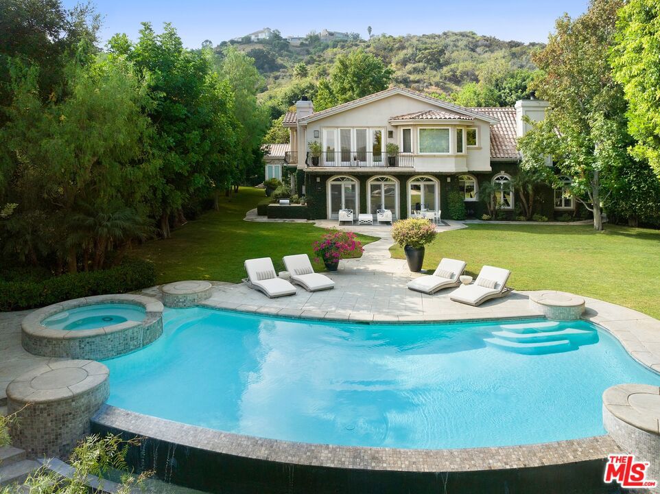 Located in the esteemed ultra-private Lockridge Estates of Fryman Canyon, this double-gated, 6-bed, 9-bath transitional masterpiece commands sophistication and offers unparalleled luxury living. Situated on over 1.5 acres of meticulously manicured grounds, the property offers expansive serene environs coupled with its ideal proximity to Studio City and the Westside. Stepping into the grand foyer, you'll be greeted by a stately staircase framed by soaring 20-foot ceilings adorned with detailed millwork throughout. Off the entryway, find a regal office space boasting custom cabinetry and exquisite wainscotting. On the opposite side of the foyer discover the formal living room graced with vaulted ceilings allowing for an abundance of natural light to fill the space. Flowing directly through to the rear living, you'll encounter the inviting, light-filled space adorned with an elegant bar along with an array of double doors, effortlessly connecting indoor and outdoor living. Framed by decant millwork, the formal dining area exudes an air of refined sophistication offering an abundance of space ideal for hosting. The butler's pantry, connecting the dining space to the kitchen, serves as a functional and stylish intermediary, complete with custom cabinetry, ample storage, and elegant finishes, ensuring seamless service for both formal occasions and everyday dining experiences. The gourmet kitchen with its oversized island sanctions as an ideal gathering spot to host friends and family. Complete with premium stainless-steel appliances, the space is outfitted to elevate any culinary experience. For more casual dining, enjoy the eat-in breakfast nook graced by the outdoor foliage and incredible natural light. Ascend to the second level to find the expansive luxe primary suite, accompanied by three additional spacious bedrooms and an inviting, elegantly designed home theatre space. Step through the grand double doors at the apex of the main staircase and enter the primary suite, where you'll find an exceptionally spacious layout. An elegant sitting area, dual primary bathrooms, each featuring their own adjoining closet space, along with multiple terraces, collectively create a luxurious environment ideal for relaxation. Outdoors, discover the notably large flat yard complete with manicured grounds, a captivating infinity pool, a putting green, numerous outdoor seating areas, and a charming rear guesthouse currently reposed as a fitness space.