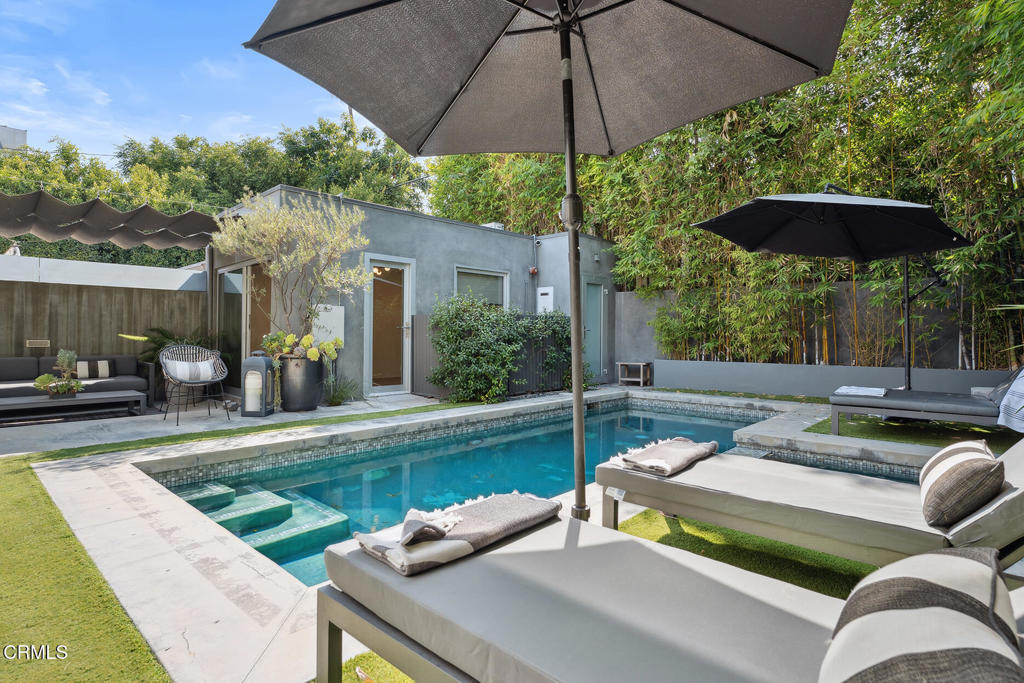 Behind sleek double gates, this architectural modern offers the ultimate in privacy, style, and comfort. Designed with clean lines and high-end finishes throughout, this residence blends form and function in every detail.The entire home is wrapped in Fleetwood windows and doors, flooding interiors with natural light while maintaining a sleek modern aesthetic. Inside, oak floors lead through a Bulthaup kitchen outfitted with Gaggenau appliances, including refrigerator, wine fridge, range with oven and steamer, plus a Miele dishwasher--a true showcase for those who appreciate culinary design. For convenience, a Miele washer and dryer complete the home's top-tier appliance package. Skylights and glass walls illuminate the open layout, connecting the kitchen, dining, and lounge areas.At the heart of the home, the dramatic Great Room features soaring 14-foot ceilings, polished concrete floors, and a contemporary fireplace. Walls of glass open to the heated saltwater pool and spa, creating seamless indoor-outdoor living.Two serene bedroom suites each offer Siberian marble baths, while thoughtful upgrades elevate everyday living--a whole-home water filtration system and air conditioning with integrated air purification.Outdoors, entertain in style with a galley kitchen complete with BBQ, sink, and prep space. A fully legal guesthouse (with certificate of occupancy) adds flexibility, offering its own grotto-style bath. Additional highlights include secured storage and a water cistern reclamation system.