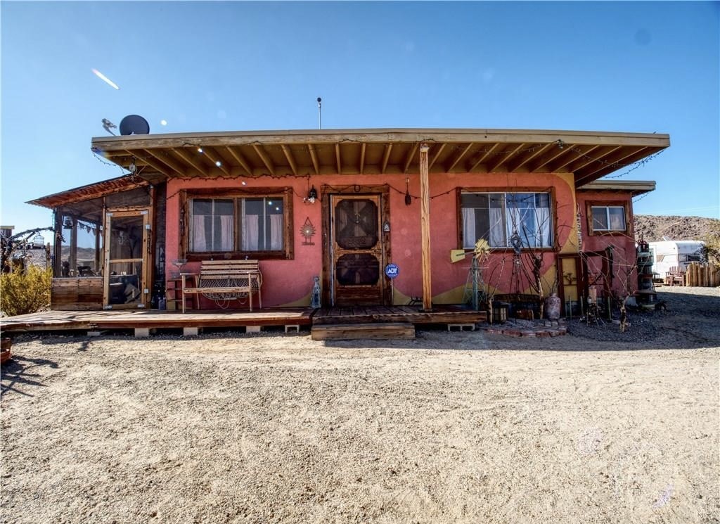 Incredible Opportunity to own a very UNIQUE & One-Of-A-Kind desert property just MINUTES from Joshua Tree National Park. This artistically revived 1958 homesteader is nicely situated on 2.5 acres of land with multiple multi-use outbuildings and stunning panoramic desert and mountain views. The main cabin adorns warm wood flooring, a brand new Mini-split, a lovely wood-burning fireplace and several large windows that let in an abundance of natural light. The quaint kitchen and dining area features a charming built-in dining nook, mounted shelving and hand-built cabinetry. The bathroom is anchored with a large clawfoot tub to soak the day away and the primary bedroom has a cozy cottage feel with a connected enclosed outdoor porch (the perfect spot to enjoy a morning cup of coffee).
Outside you'll be delighted to find a covered dining area with a cob oven, a convenient laundry closet, a fenced-in lounge or pet area, a colorful performance stage, an outdoor shower & loo and a playful art pathway connecting all the varying art installations. These Site structures include two workshops, a 120 sqft guest cabin, two guest pods, a 1970 trailer named "LUCY" and plenty of additional space to entertain or simply relax around a firepit on a starry desert night. There are also RV hook-ups for the traveling guests! This charmingly eccentric compound would make for a great artist's retreat or someone's serene sanctuary away from all the hustle & bustle. It's a less than 15 min drive to downtown Joshua Tree, downtown 29 Palms, eateries, vintage shopping & more but still far enough away to fully immerse yourself in all the beauty the desert has to offer. Come take a look and let this home's calming and captivating allure do the rest. Your new desert home or weekend retreat awaits!