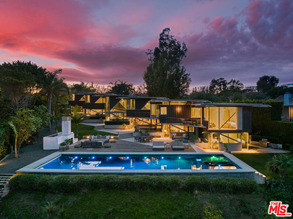 Ocean views, lush natural light, and dramatic angles animate the spacious interiors of this spectacular architectural estate. Designed by renowned architect Bart Prince in a series of interconnected modules, the home follows the contours of a gently terraced gated property of over an acre. With a guest house, pool, expansive landscaped grounds, and Riviera 3 beach key, this singular residence is an entirely original Point Dume retreat. The generous use of structural steel, soaring ceilings, walls of glass, polished concrete floors, and lustrous wood create welcoming spaces that seem to erase the boundary between indoors and out. Contemporary lines and exceptional layout provide settings for comfortable living and inspired entertaining. Two living rooms, a family room, and a dining room with a fireplace all offer tantalizing views of the very private grounds, where patios and gardens suggest congenial gatherings, barbecues, and undisturbed relaxation. The kitchen is a majestic achievement, with maple floors, granite countertops, top-of-the-line built-in appliances, a large island with bar seating, a built-in desk, and a butler's pantry / catering kitchen with additional appliances and a door to the side yard. An en-suite bedroom/gym/office with backyard and pool views completes the main floor. On the upper floor, where rooms are connected by a long catwalk, there is an ocean-view office with a fireplace, plus three en-suite bedrooms, including the primary. This lavish private getaway has very high ceilings and stunning pool and ocean views, plus walk-in closets and a sublime ocean-view bathroom. In addition to the main house, there is a one-bedroom guest house with a living room and a full kitchen. At the front of the house, there is a lush, private yard with ample space for relaxing and entertaining. The grand-scale ocean-view backyard offers a variety of settings for outdoor dining and lounging, including a covered dining deck, an outdoor living room, a large fireplace, lawn, sauna, large swimming pool, and ocean-view pathways that meander among a fruit orchard with private steps that descend to the beach below. The gated property is served by two driveways, one leading to the four connected, glass-door garage bays, one with a full bath. Additional features include seven-zone climate control and air conditioning, heated concrete floors, and security system. This is a remarkable architectural estate of bold design in a marvelous setting.