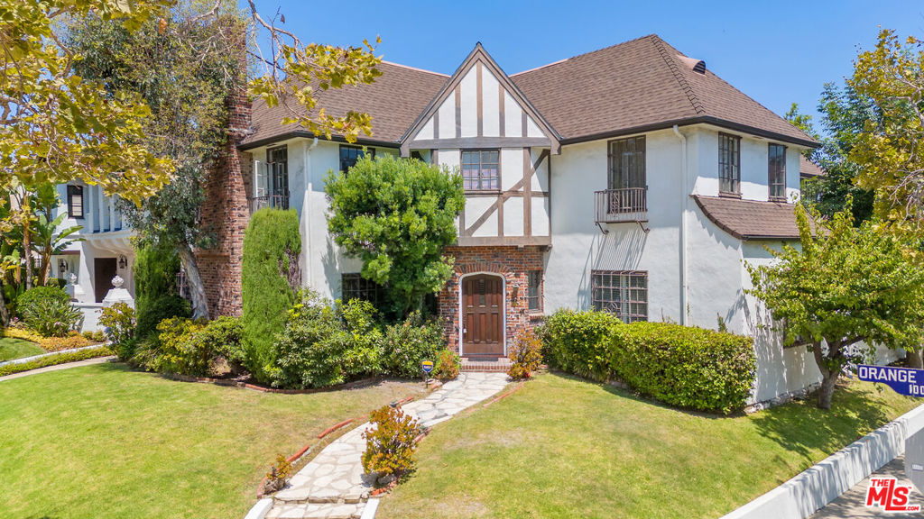 Discover this expansive 4 bed, 3 bath residence, occupying the entire lower half of a stately English Country duplex in the heart of the historic Hancock Park neighborhood. Brimming with timeless architectural details and an abundance of space, this home offers both elegance and comfort. The sunlit living room sets the tone with its decorative fireplace, original built-in shelving, original floors, and an abundance of windows, creating a warm, inviting atmosphere. A formal dining room offers an ideal setting for gatherings, seamlessly connecting to a generous-sized kitchen enhanced with quartz countertops, two separate sinks for dietary needs, ample cabinet storage, and a cozy breakfast nook perfect for morning coffee or casual meals. Just beyond, a designated laundry area that leads to a private bedroom and a full bathroom with a shower. A long hallway connects to the main bedrooms, where the massive primary suite offers a true retreat with a bonus sitting area, dual closets, and an en-suite full bath. Two additional spacious bedrooms share a charming dressing area and a bathroom featuring both a tub and a shower, providing comfort and convenience. Outside, enjoy your own private patio which connects to a large shared backyard, along with one garage parking space. This is a rare opportunity to enjoy the elegance and space of Hancock Park living in a home that radiates warmth and style.