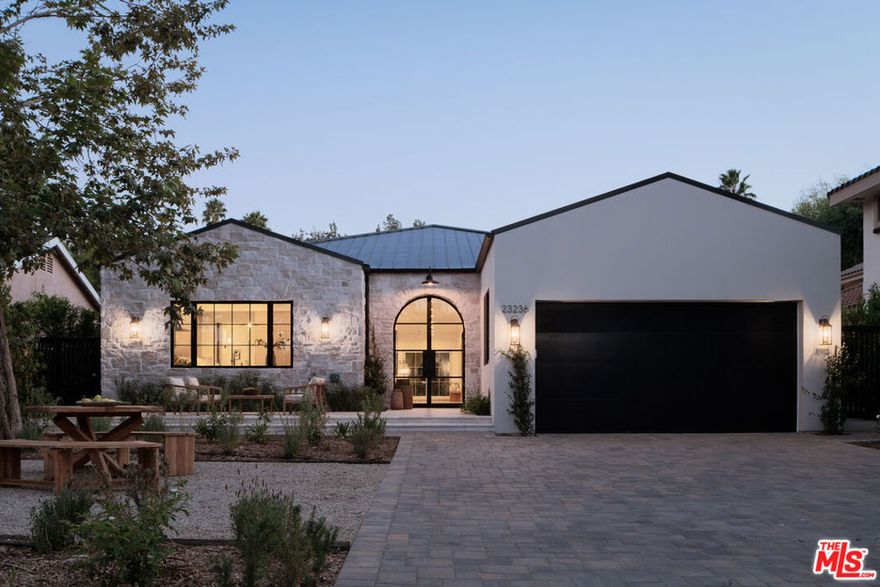 Presenting this 2025-built single-story modern farmhouse compound, gated and set back from the street with a pickleball court, numerous outdoor gathering spaces, and sparkling pool and spa in Walnut Acres Estates. The home's cobblestone and soft stucco facade blends natural elements to form a serene, welcoming environment for all to enjoy. Guests arrive into a sizable motor court amidst carefully placed drought-tolerant landscaping and cozy sitting areas under shade trees. Through a beautiful curved glass-paned front door, visitors discover high ceilings, warm woods, and organic hues throughout, calming the senses. The living room is centered by a stone fireplace flanked by thoughtfully designed built-in book cases that continue the home's casual, artistic vibe. The kitchen is grand and elegant, with custom cabinetry, state-of-the-art appliances including a commercial-grade range with smartly designed hood plus pot filler, and oversized center island. The adjacent butler's pantry perfectly connects to the formal dining room for catering and entertaining. Nearby is a glass-encased wine cellar, as attractive as it is functional, and a plush theatre/screening room for movie nights at home. A series of arched windows lines the hall to the owner's wing. Here, sliding glass opens to gardens and patios for effortless indoor-outdoor living. The primary bath is large, with a dual-sink vanity, soaking tub, and rainwater shower adjacent to the walk-in wardrobe with custom built-ins. Secondary bedrooms are also en-suite, and one is currently utilized as an office. Privacy hedges surround the backyard, with its variety of spaces to relax, recline, and converse, including a covered outdoor living room, al-fresco dining area, and barbecue with prep sink and bar ledge. Enjoy the shimmering waters of the pool and spa, roam and play on the grassy lawn, or challenge friends to a game of pickleball or basketball on the sport court. This is the place where memories are made! Welcome to an ideal location close to parks, schools, houses of worship, and the 101 Freeway, just moments to the Calabasas Commons, Westfield Topanga and Village, and upcoming Rams Village at Warner Center. Also located within the attendance boundaries of top-rated Woodlake Avenue Elementary School.