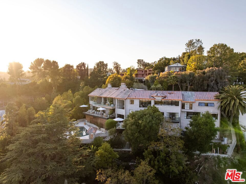 Nestled in the coveted Crest Streets of Beverly Hills, this contemporary estate blends timeless architectural pedigree with striking modern design. Originally built in 1926 as one of the model homes for the visionary Beverly Crest development by George Read, the residence stands as a piece of Los Angeles history, once said to be the home of legendary Hollywood architect John Elgin Woolf during the 1950s and '60s. Fresh from an extensive renovation, the home now showcases warm modern interiors with clean lines, natural materials, and walls of steel windows and glass that frame sweeping, unobstructed views from downtown Los Angeles to the Pacific Ocean. Designed for both privacy and openness, the living spaces flow effortlessly to expansive outdoor terraces, lush gardens, and a serene pool oasis. Set on a verdant 19,154-square-foot lot, this gated property offers rare seclusion just minutes from the heart of Beverly Hills. A truly unique offering, where old Hollywood heritage meets sophisticated contemporary living. APN 4350-016-011 also included in sale.